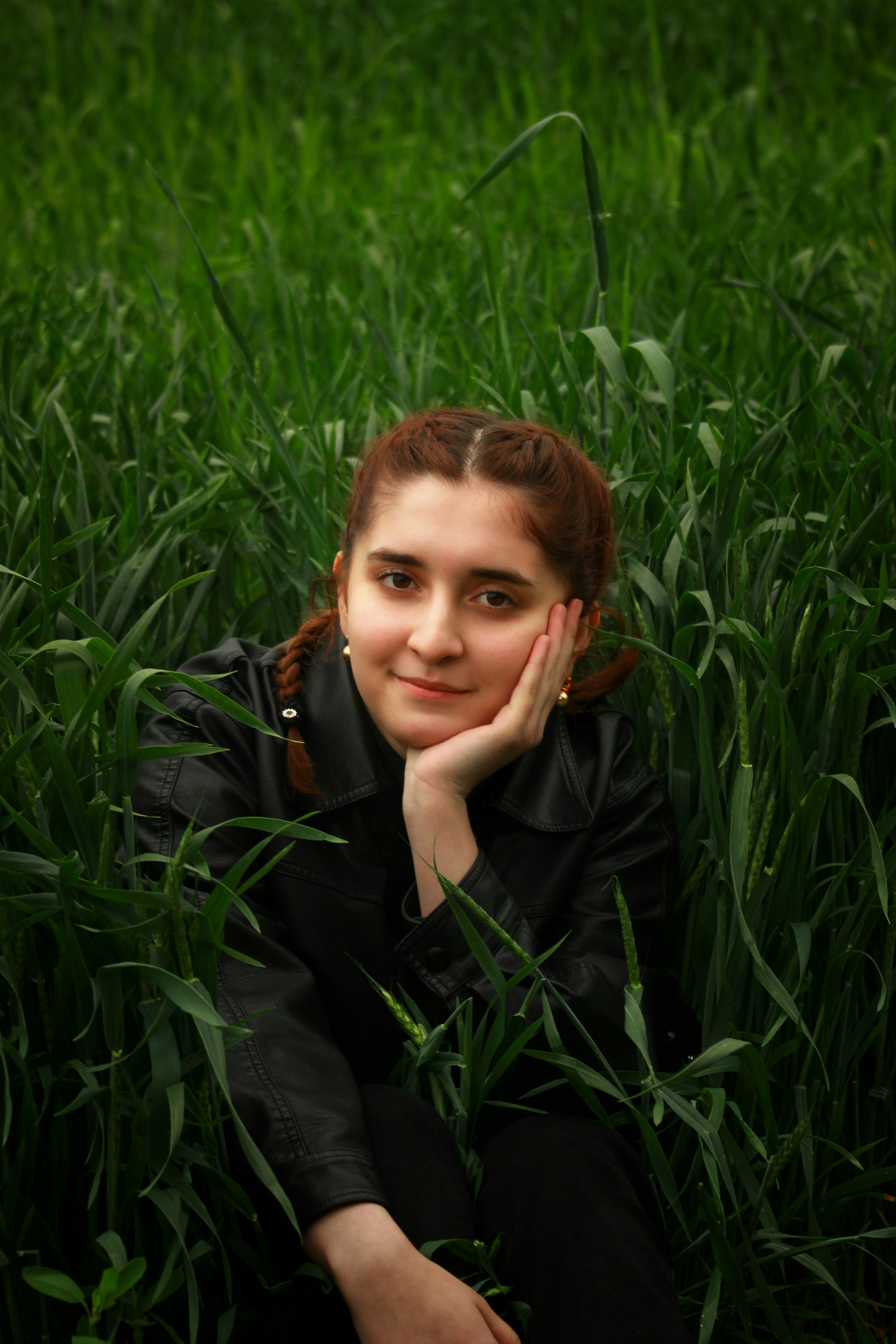 Young woman with braided hair in tall green grass.