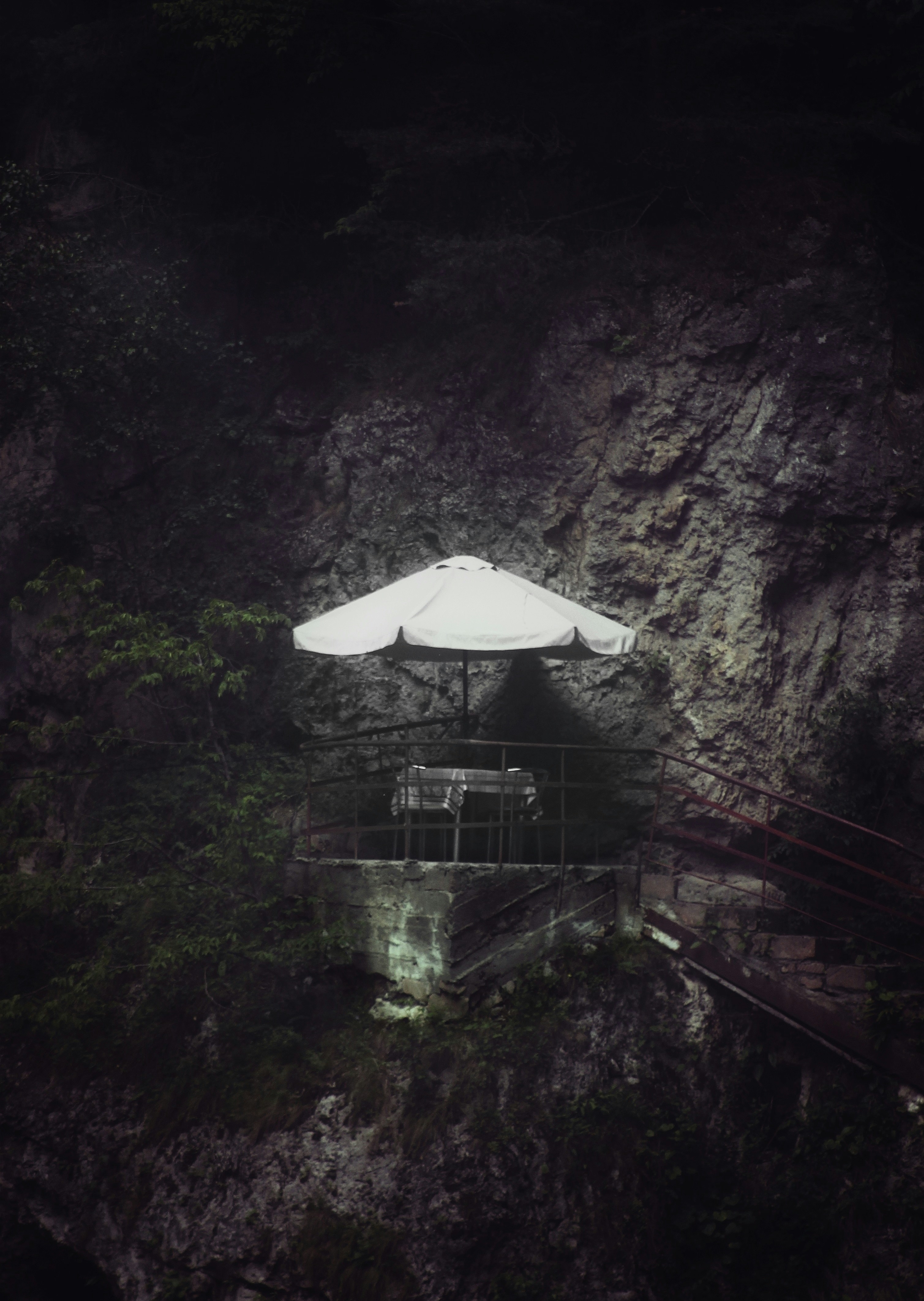 A secluded table with an umbrella on a cliffside