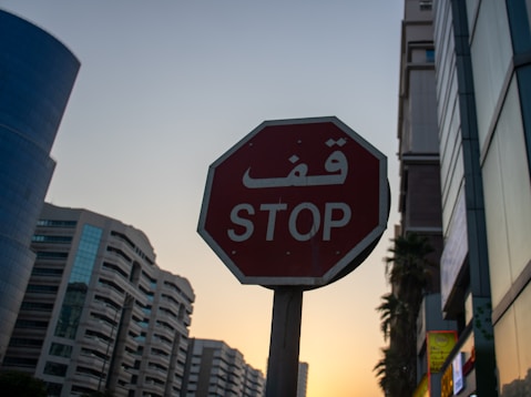 Stop sign with arabic script against sunset sky