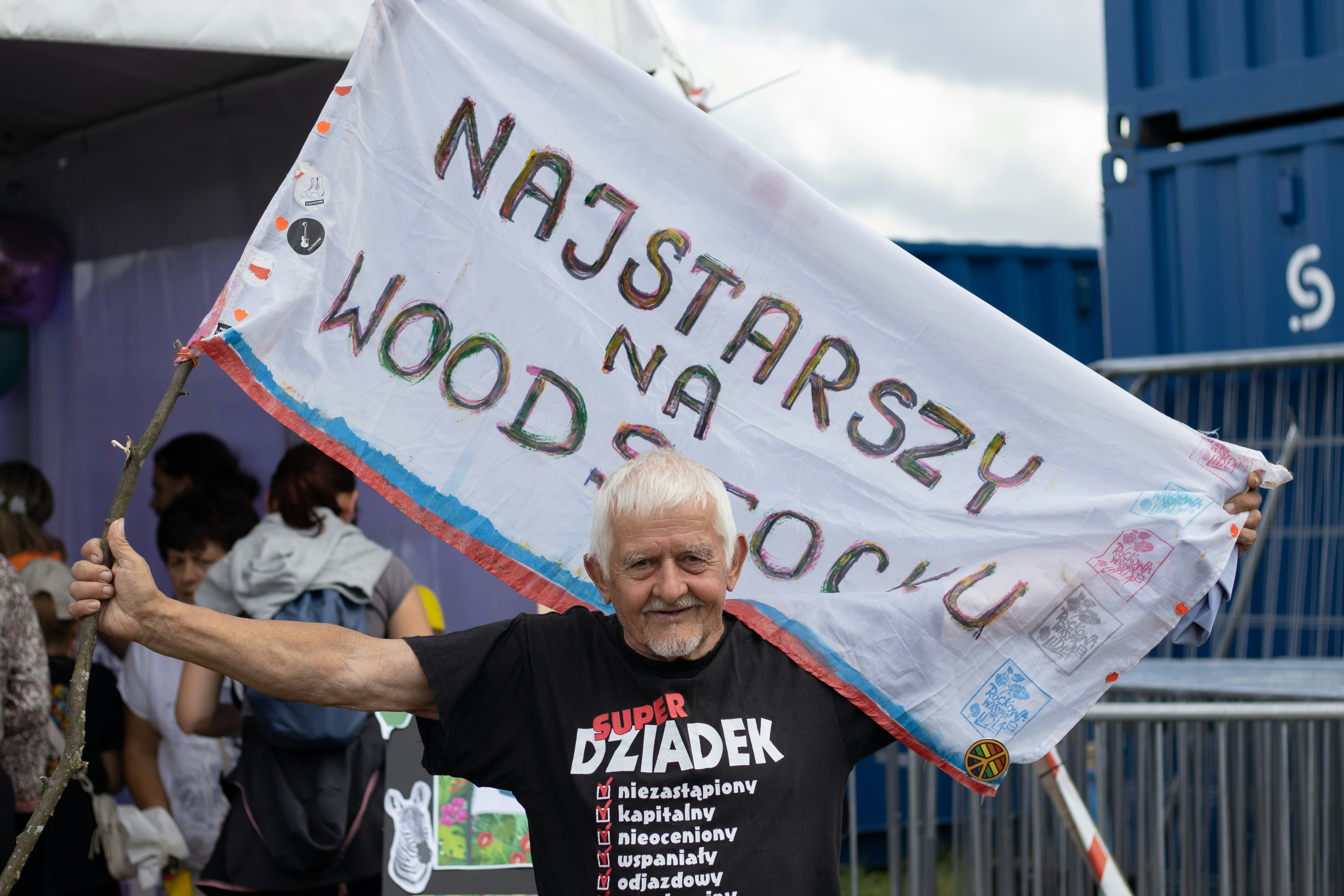 Man holds a banner with polish text and wears a t-shirt.