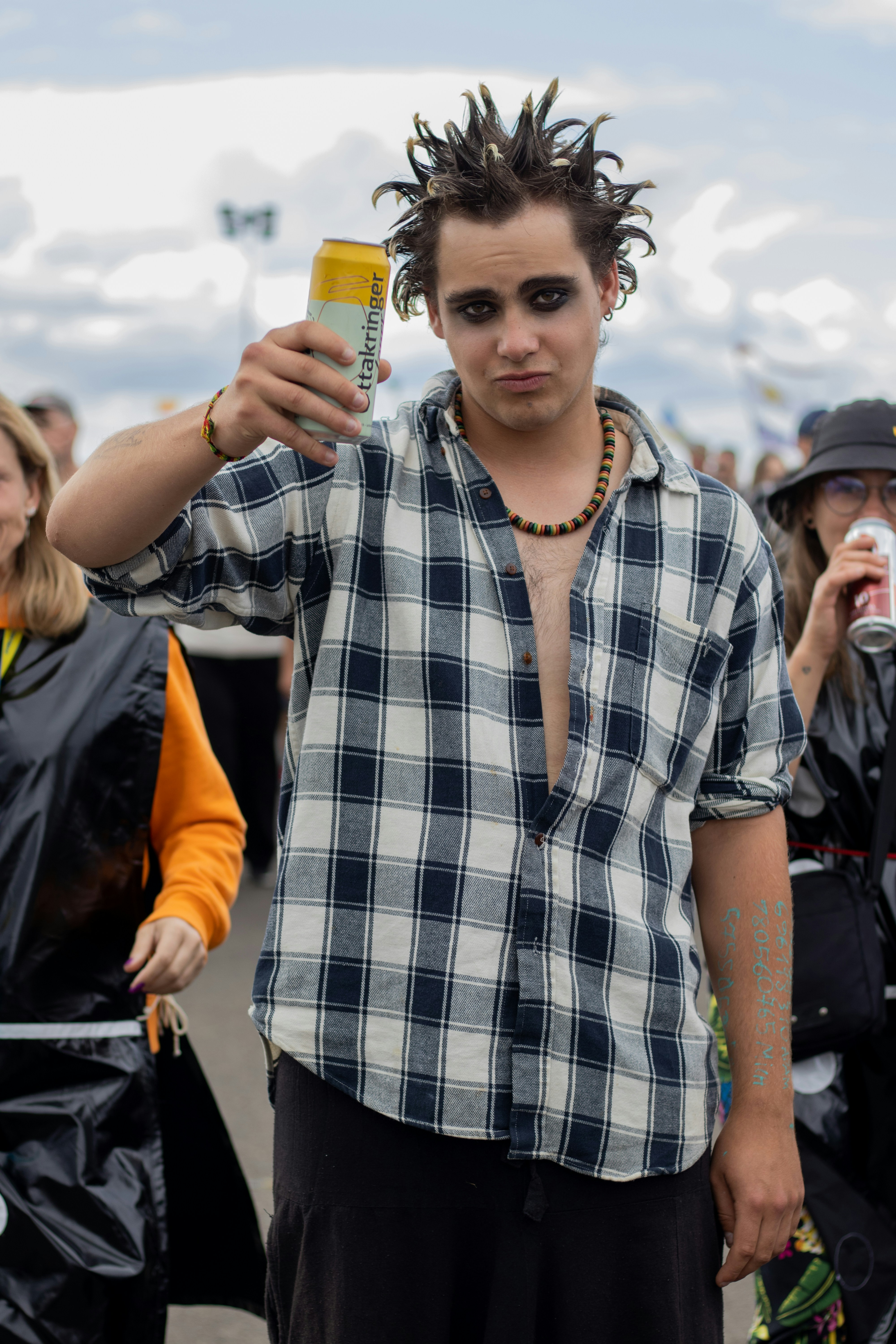 Young man with spiky hair holds up a drink.