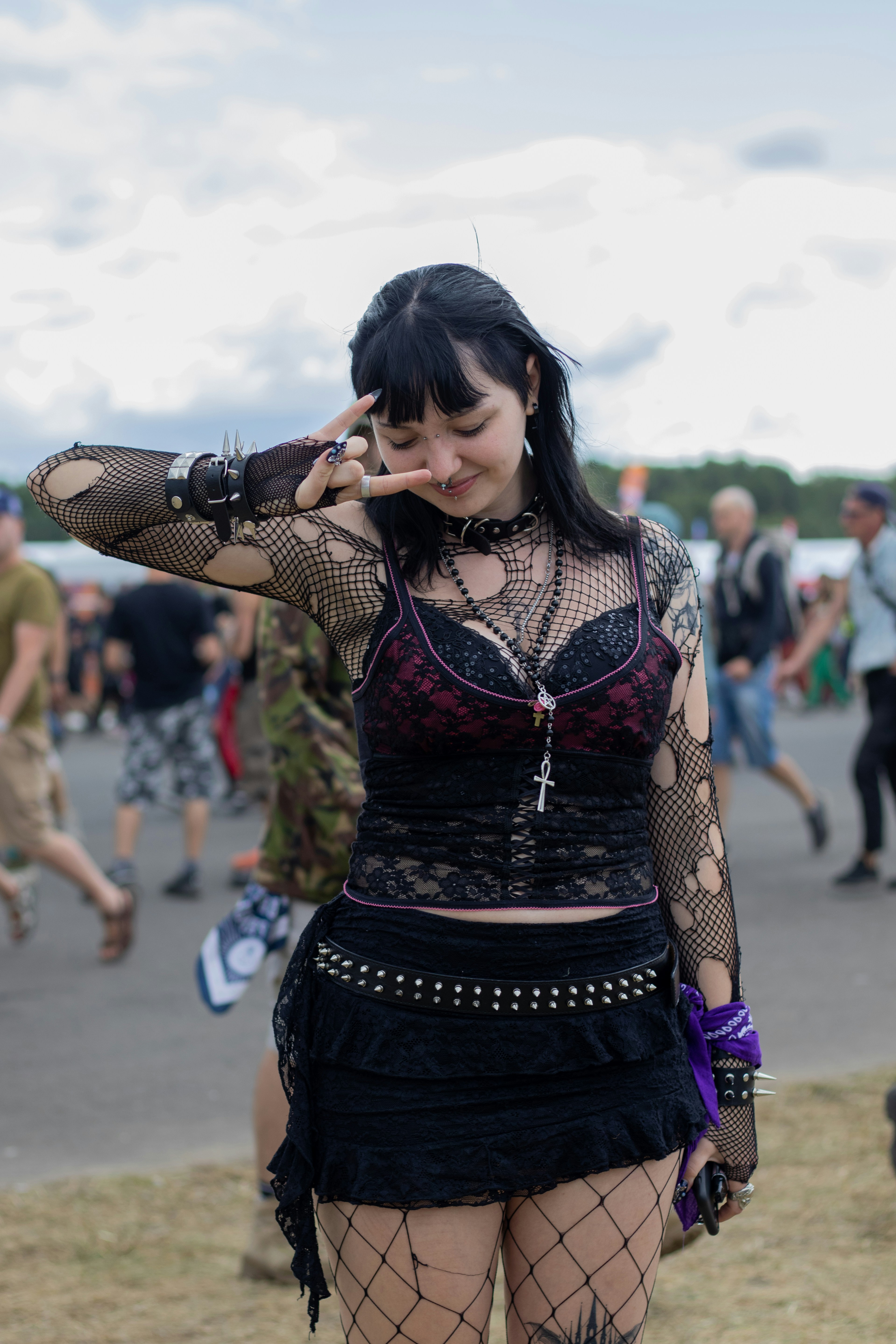 Woman in gothic attire making peace sign at festival
