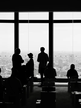 Silhouetted people looking out large windows at city