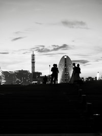 Silhouettes of people against a city skyline at dusk
