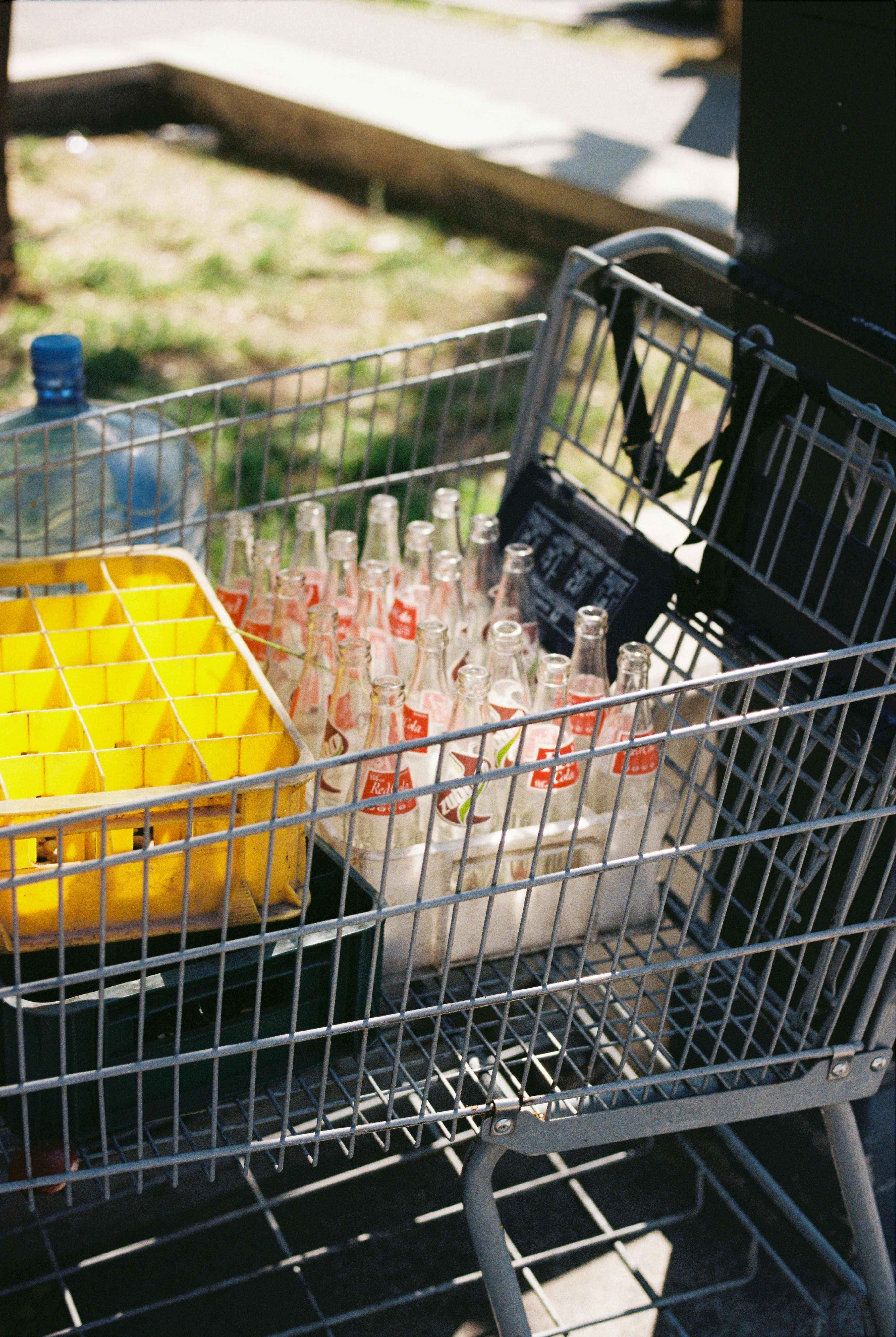Shopping cart filled with empty glass bottles and yellow crate