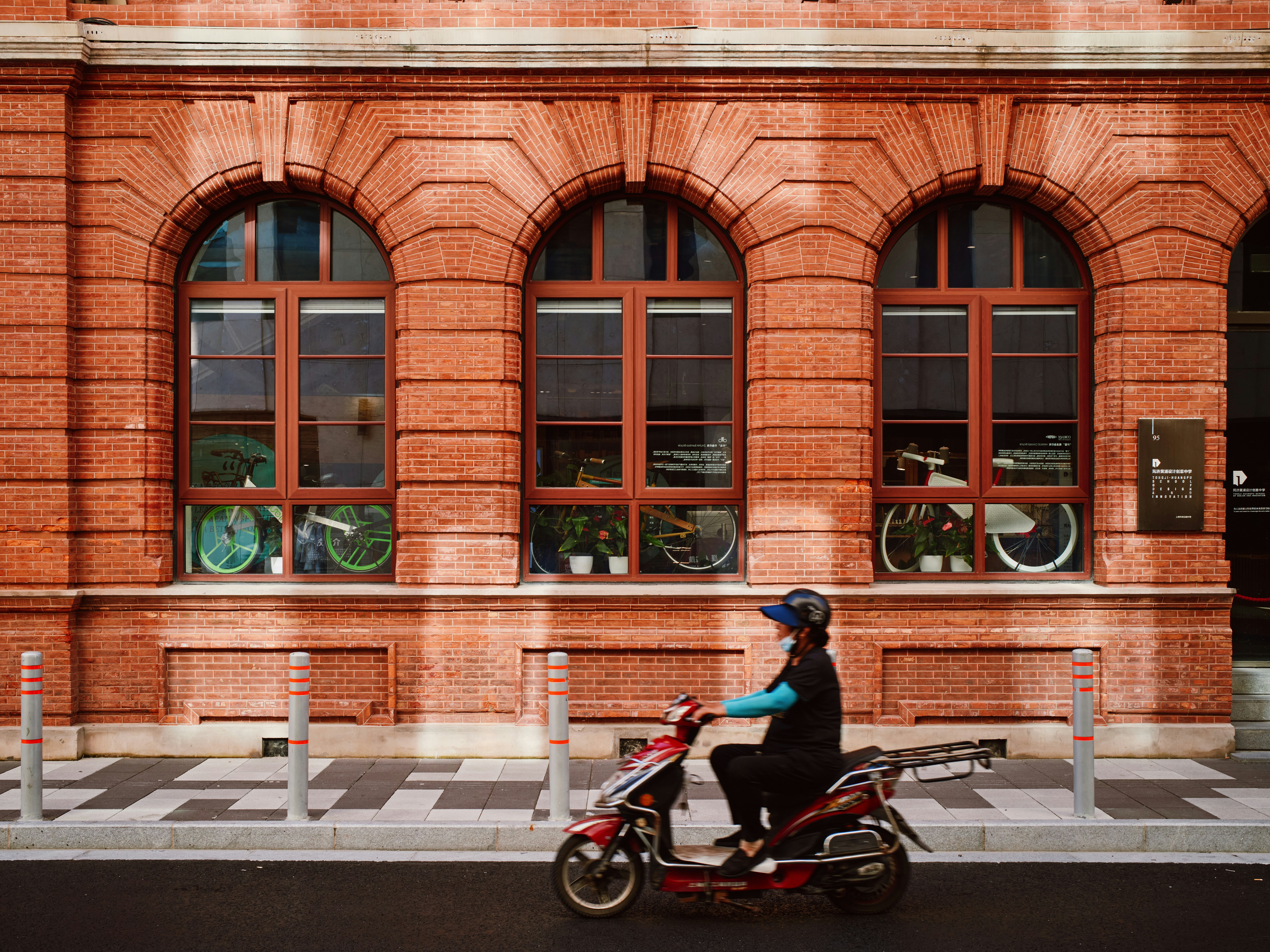 Person, die an einem Backsteingebäude vorbeifährt, fährt mit Elektroroller vorbei