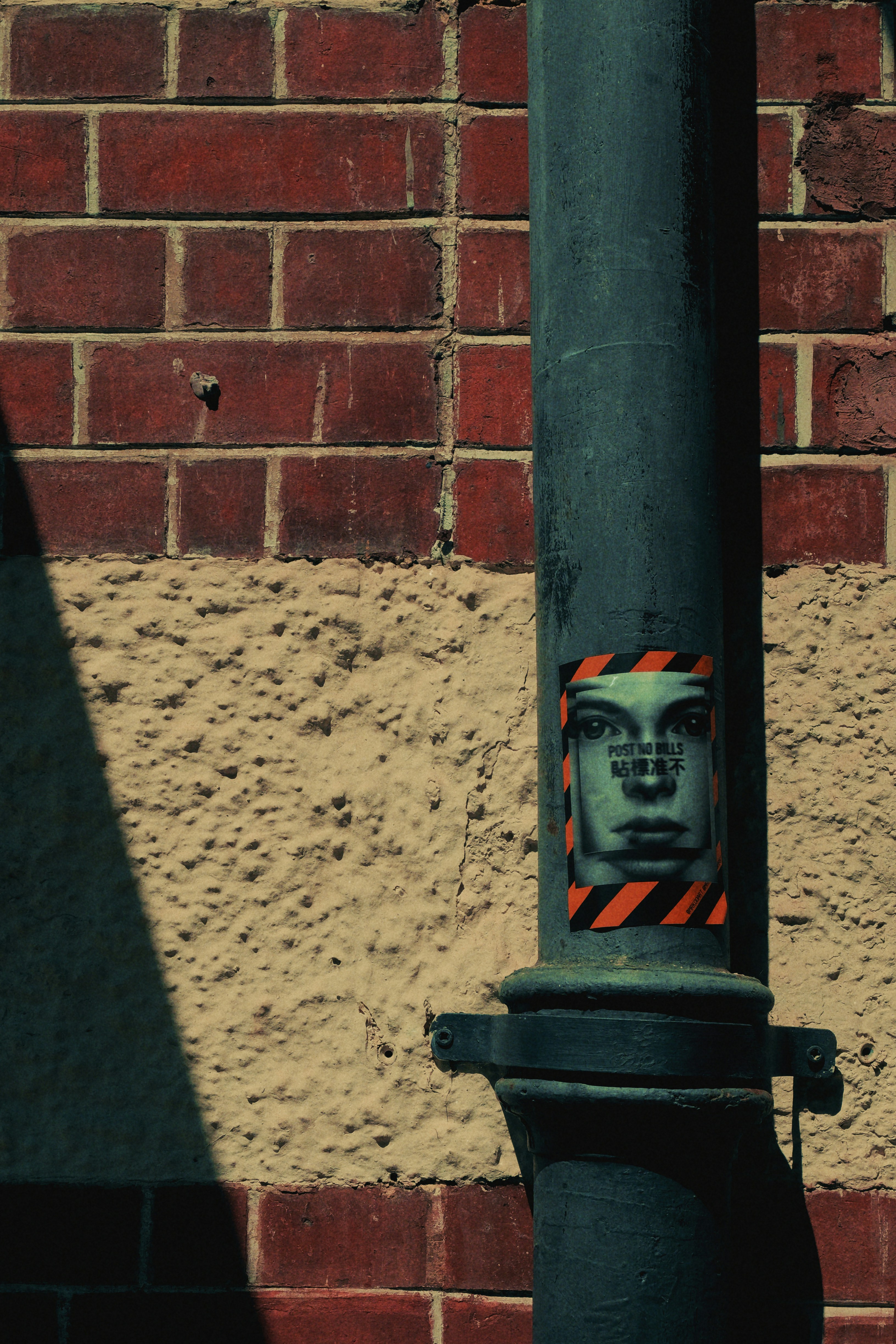Street lamp with sticker next to brick wall