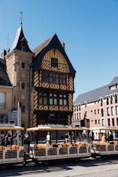 Tourists ride a train past historic buildings.