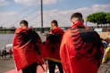Three men wear albanian flags over their shoulders.