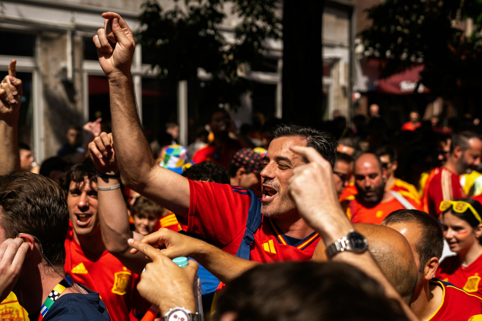 Soccer fans in red shirts cheering with raised arms during a match