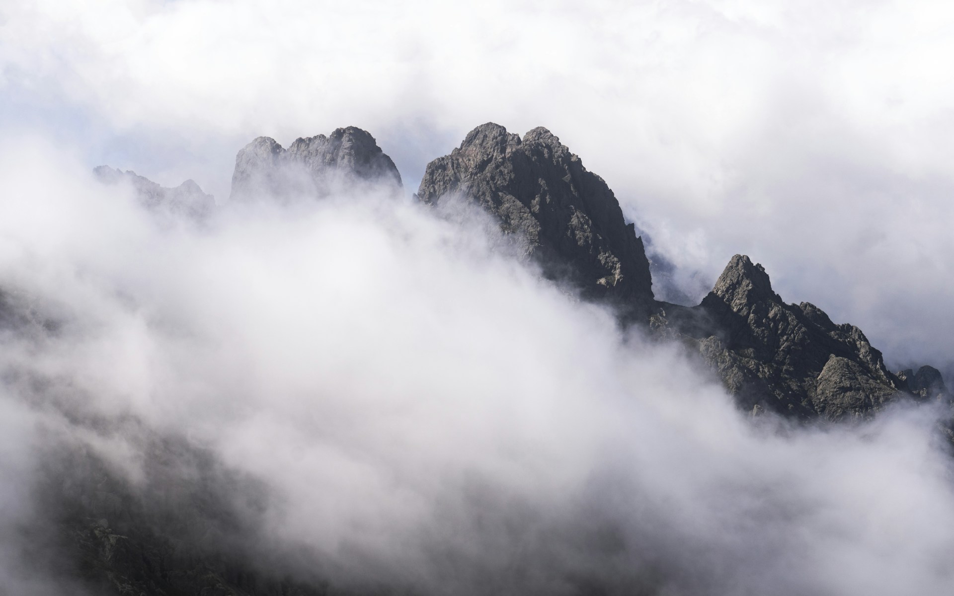 Jagged mountain peaks emerge from swirling clouds
