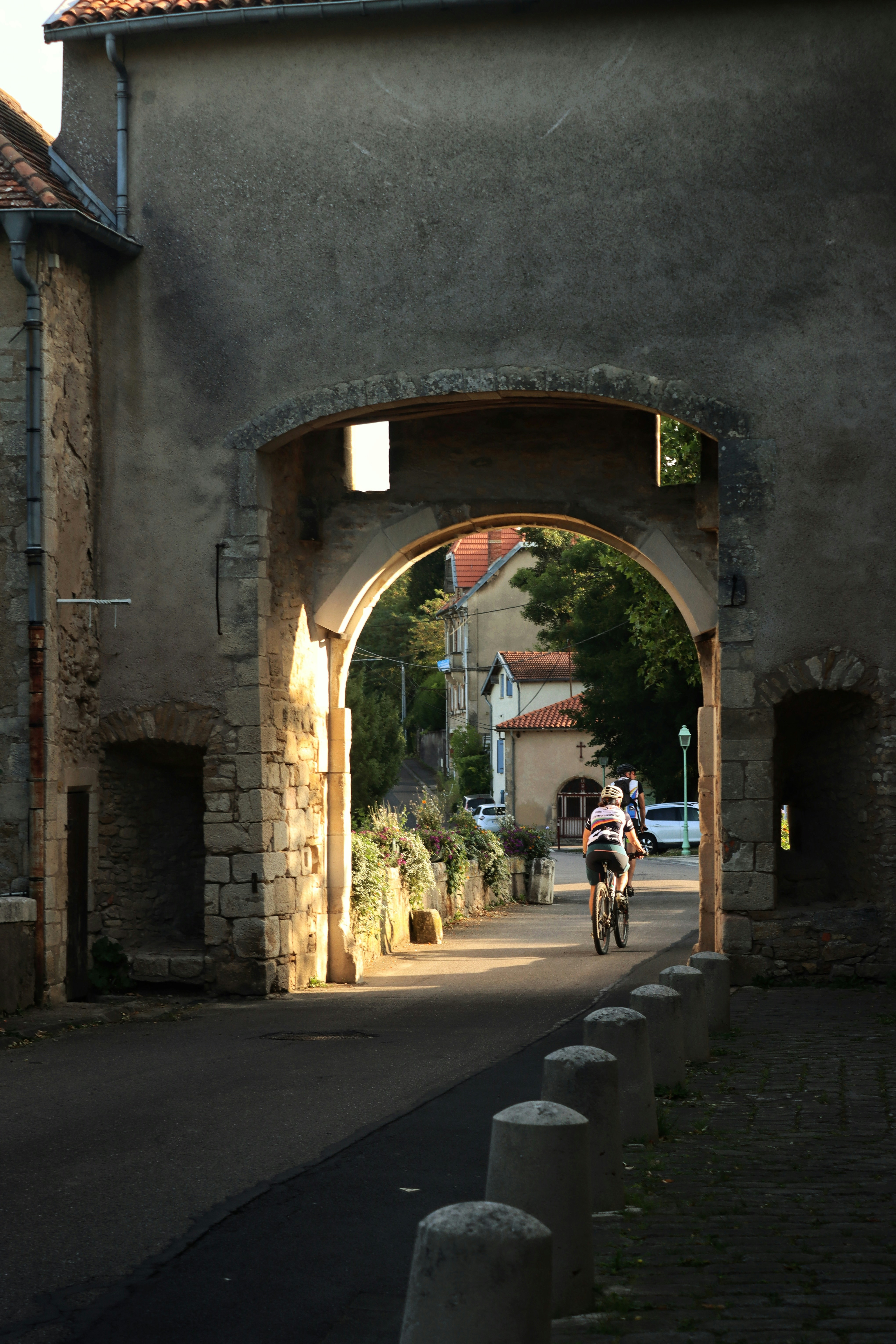 Cyclists pass through an old stone archway.