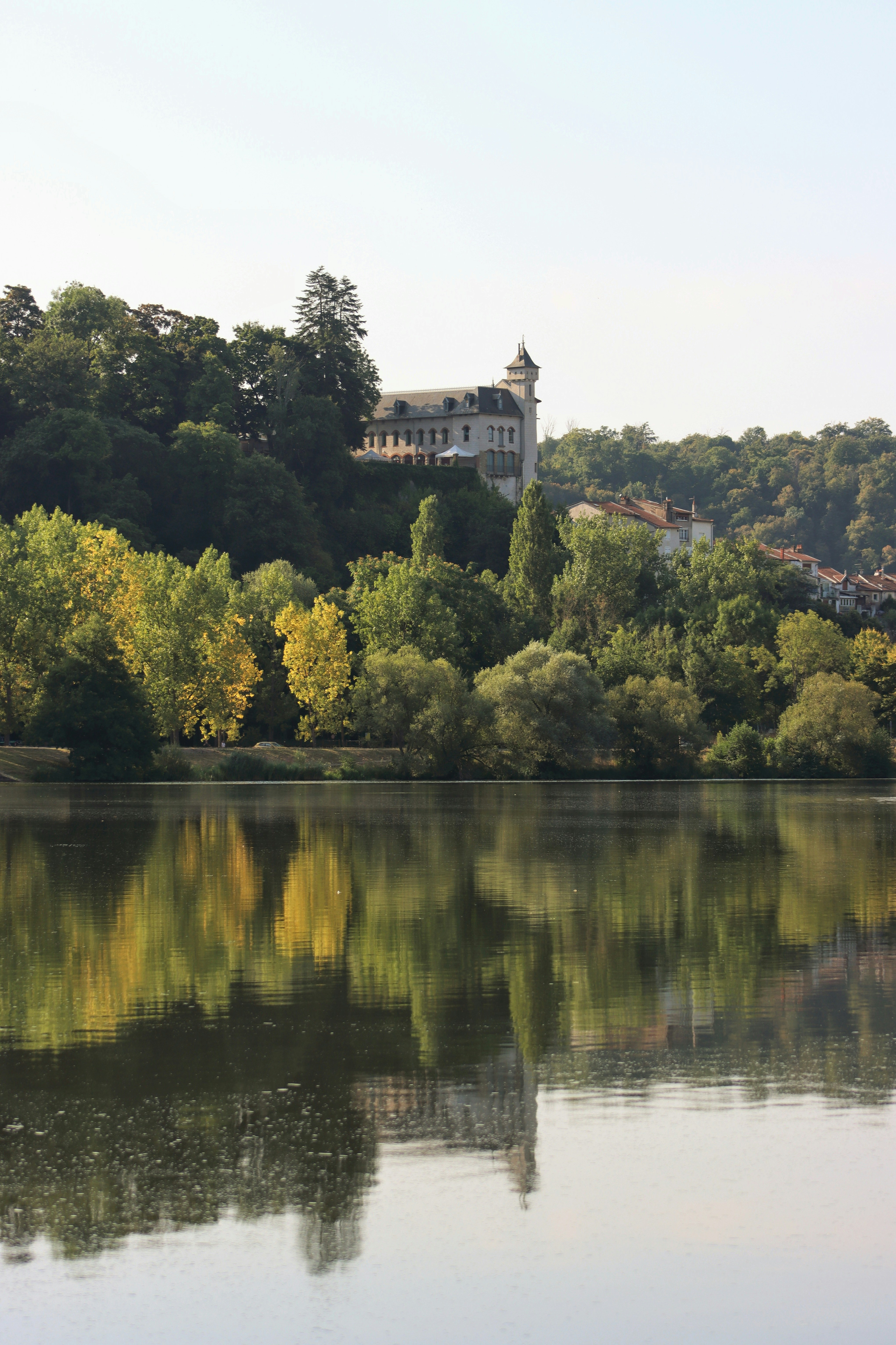 White building on a hill overlooking a lake