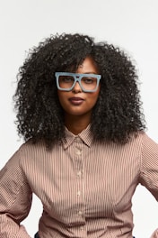 Woman with curly hair wearing glasses and striped shirt