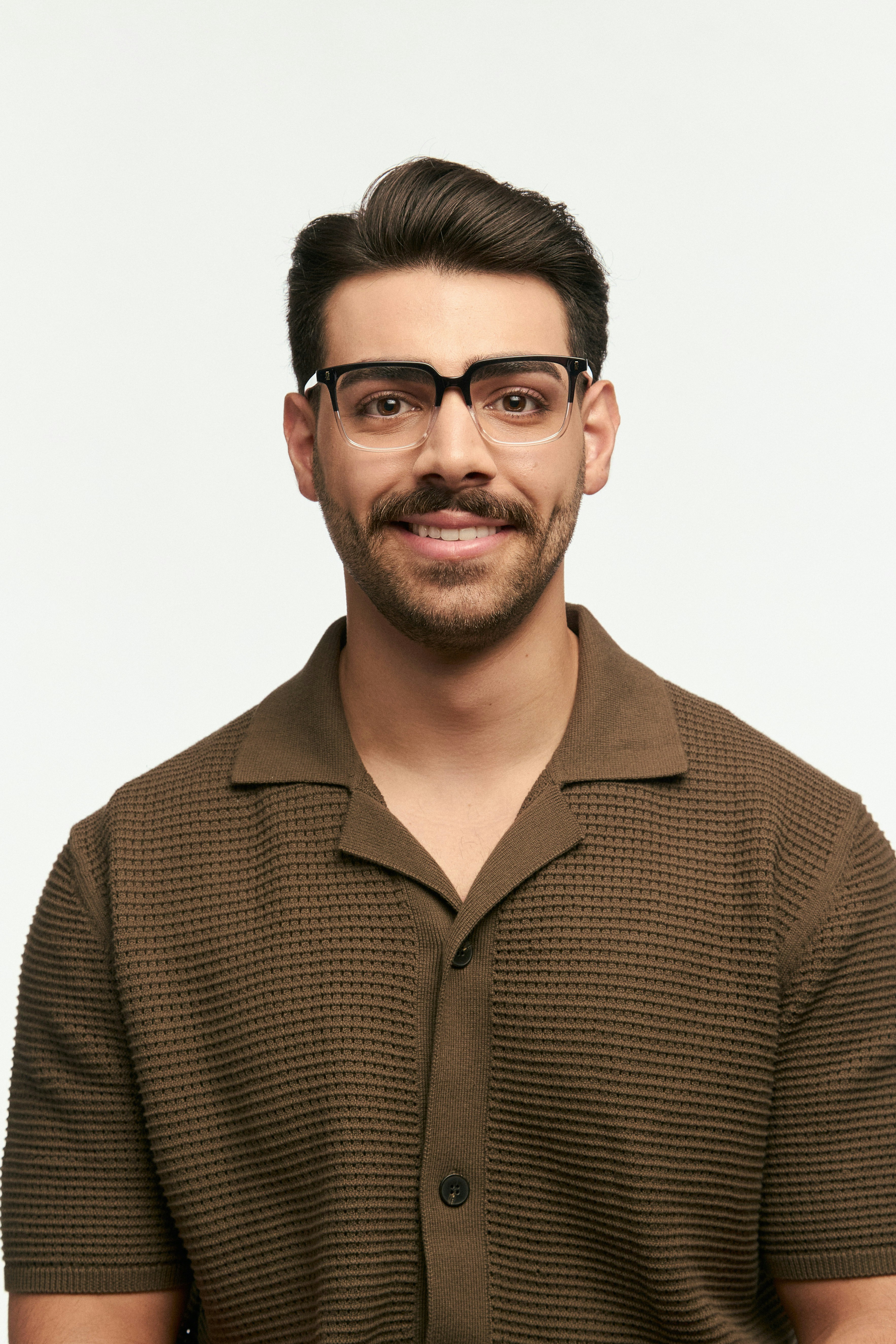 Man with glasses smiling against a white background