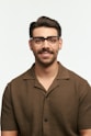 Man with glasses smiling against a white background