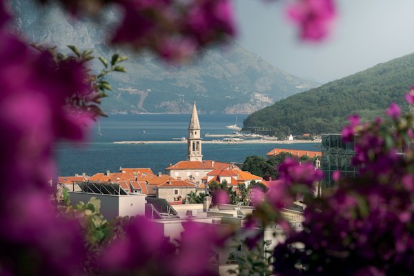 Coastal town with bell tower and mountains behind — Budva, Montenegro