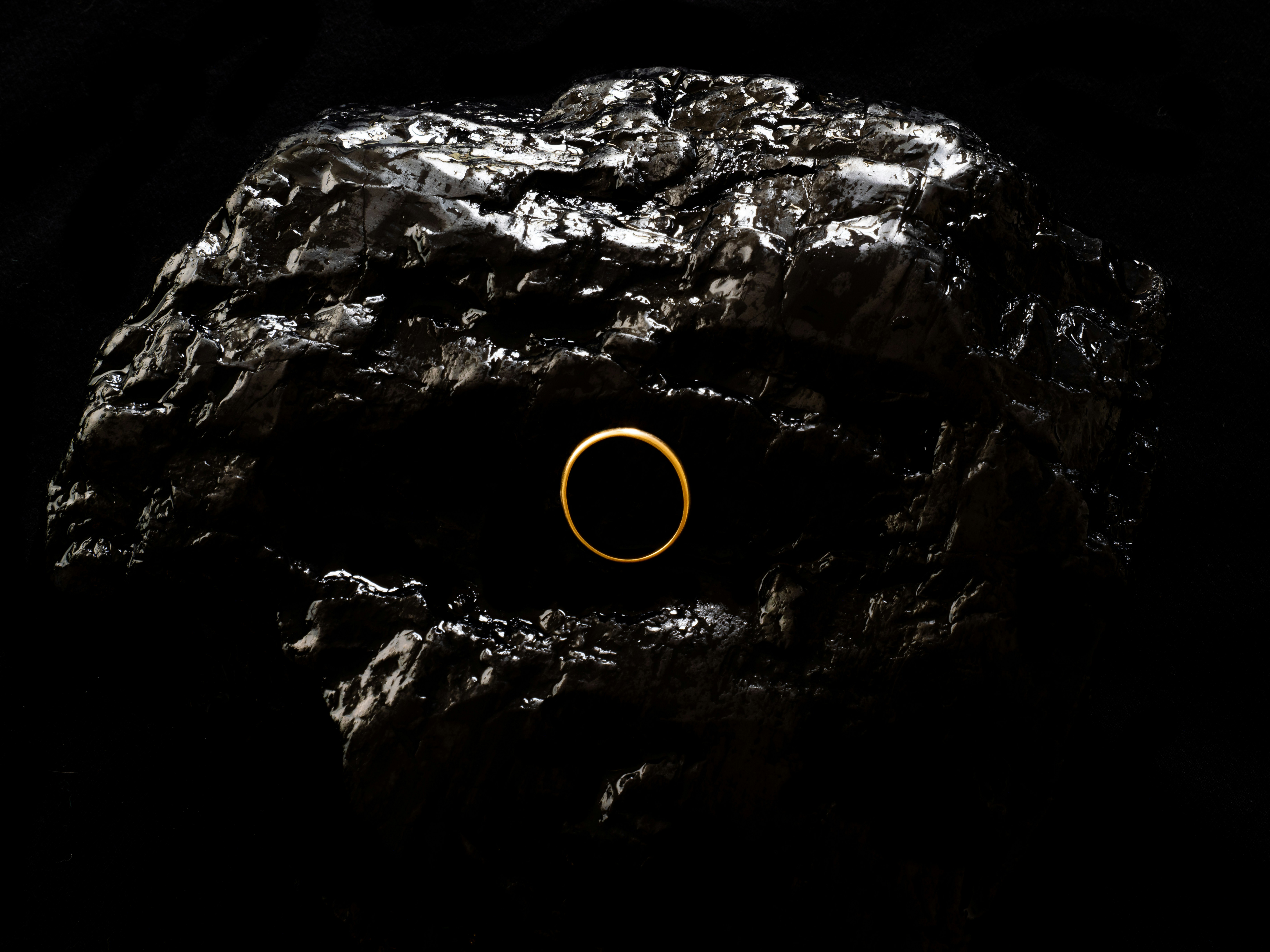 A gold ring rests in a pile of coal.