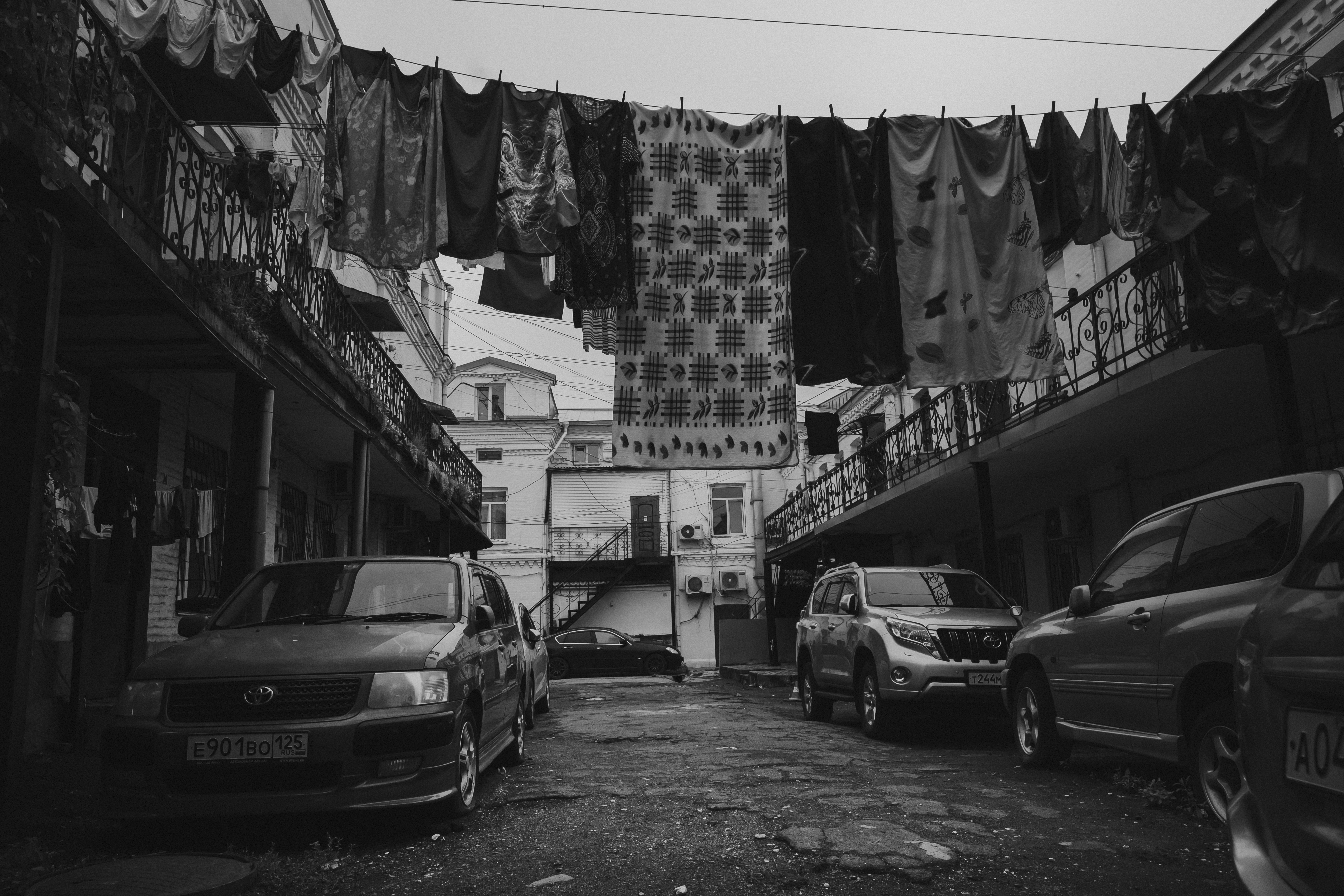 Cars parked in a narrow alley with laundry overhead