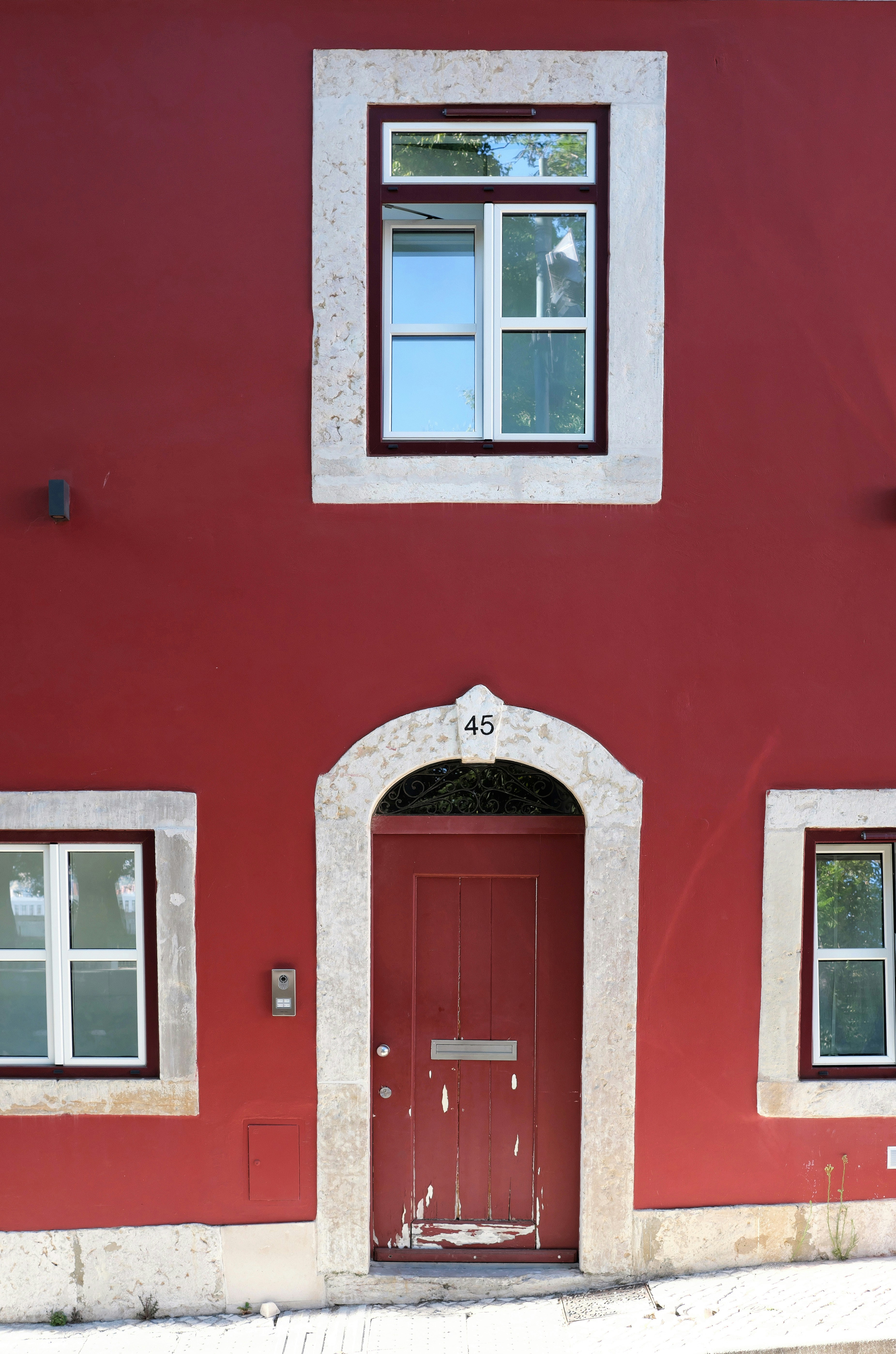 Rote Gebäudefassade mit Holztür und Holzfenstern