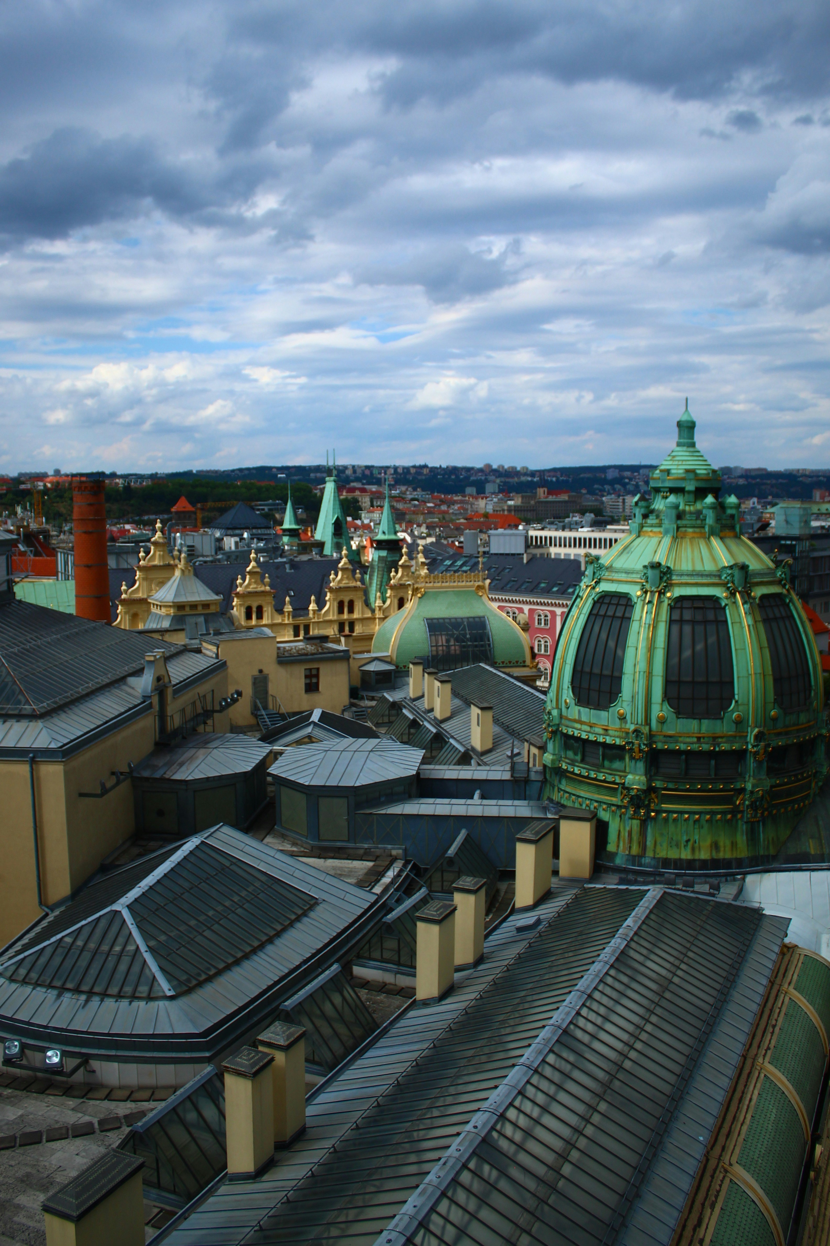 Green domes and rooftops under cloudy sky
