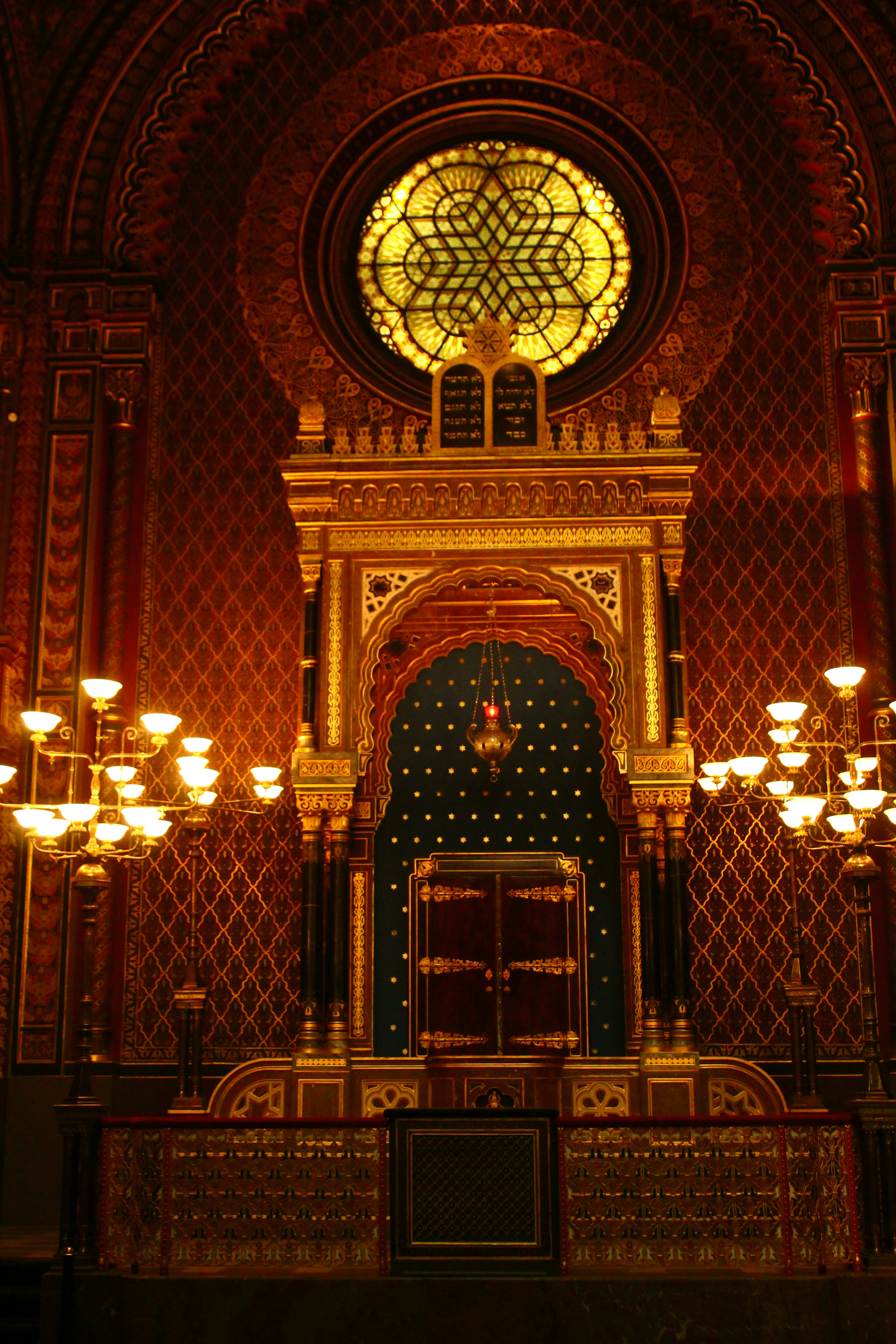 Ornate synagogue interior with stained glass and chandeliers