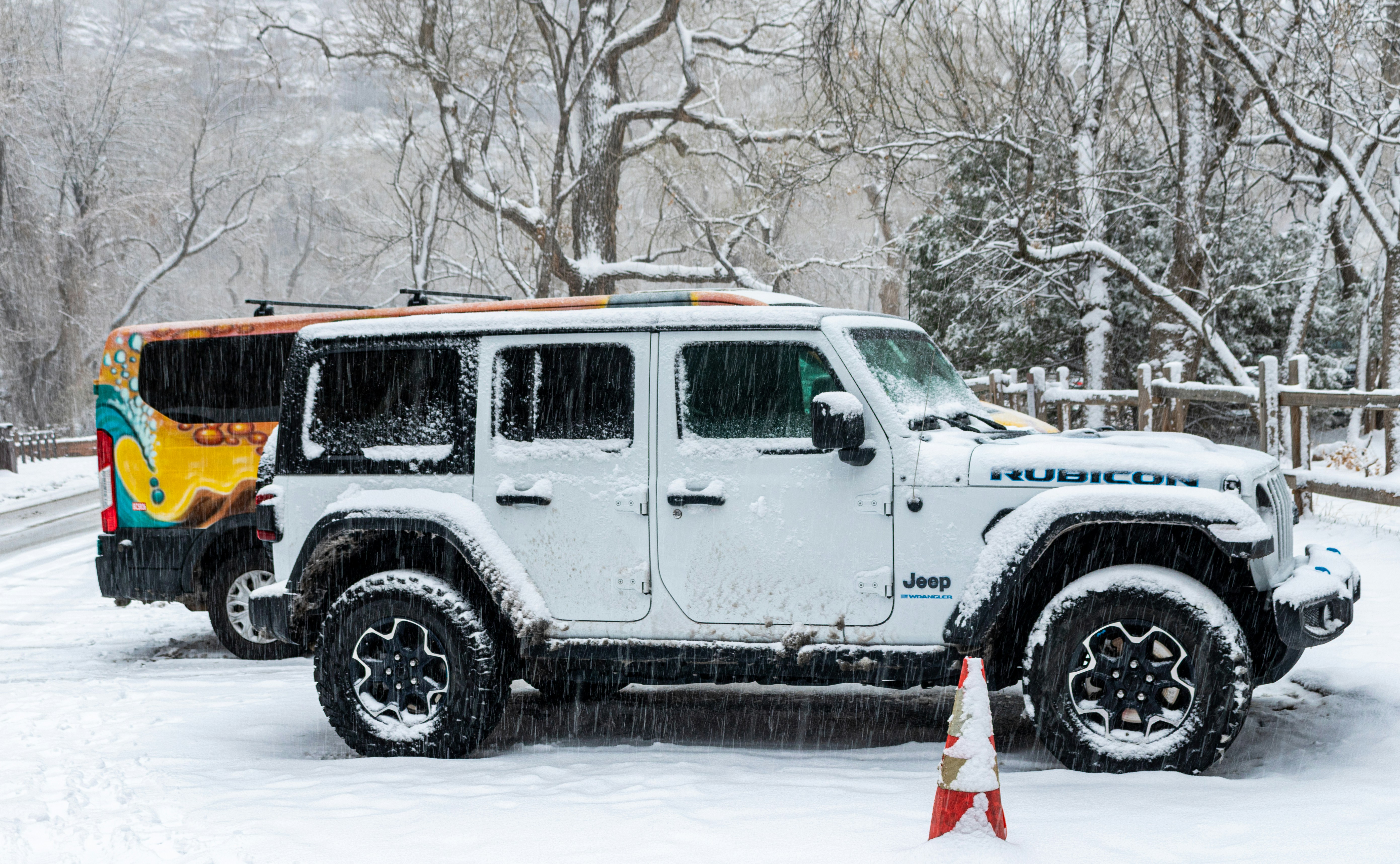White jeep parked in snow with trees