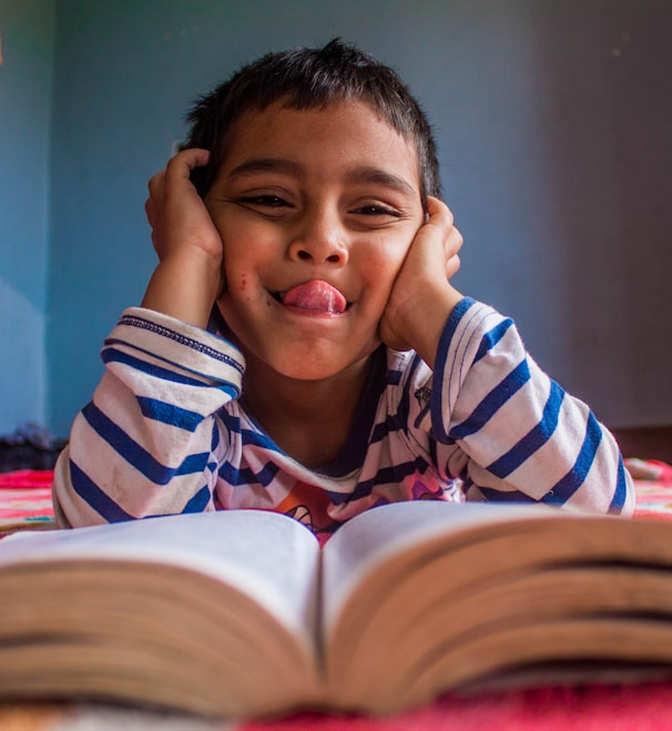 Young boy sticking tongue out at book