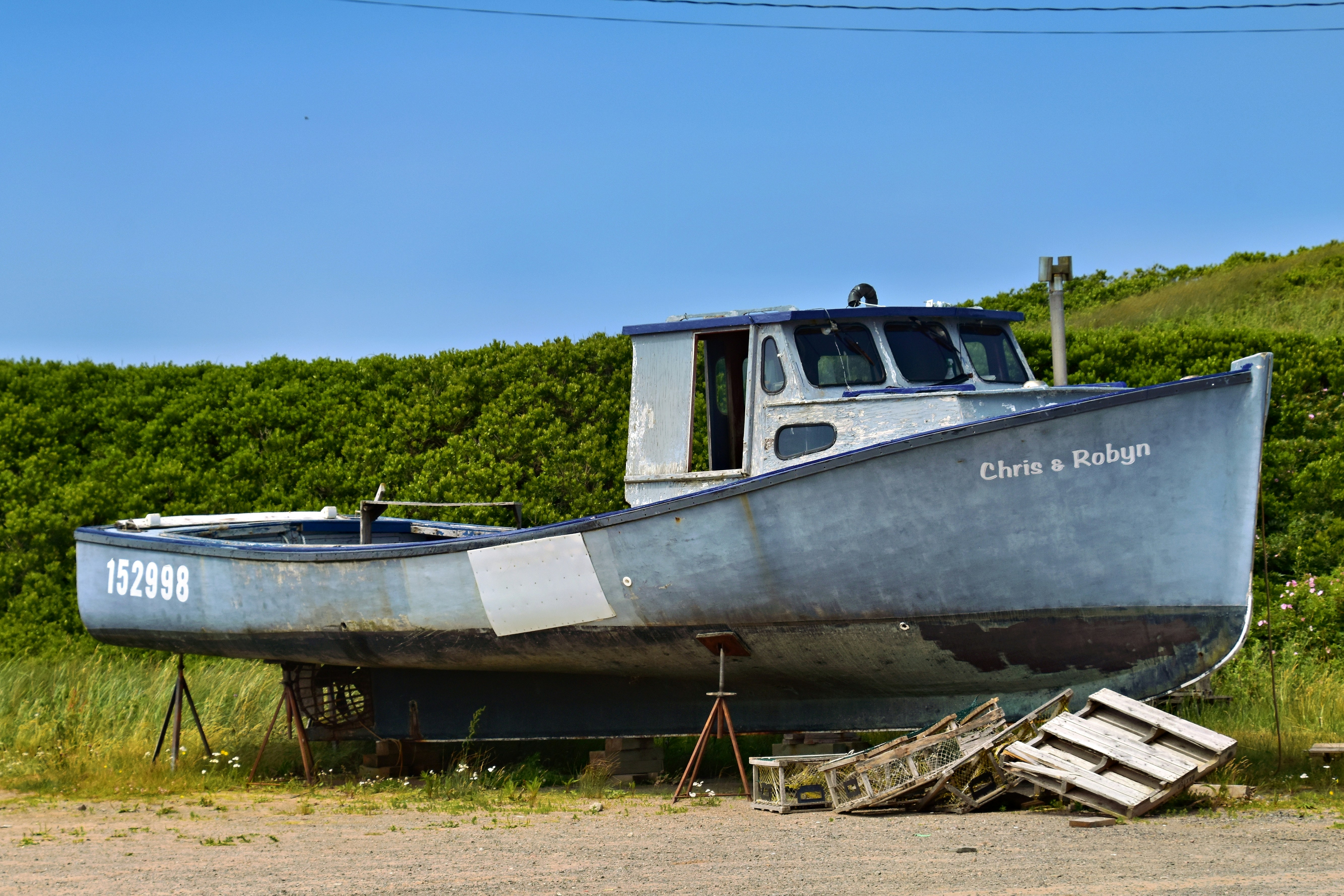A weathered fishing boat rests on land