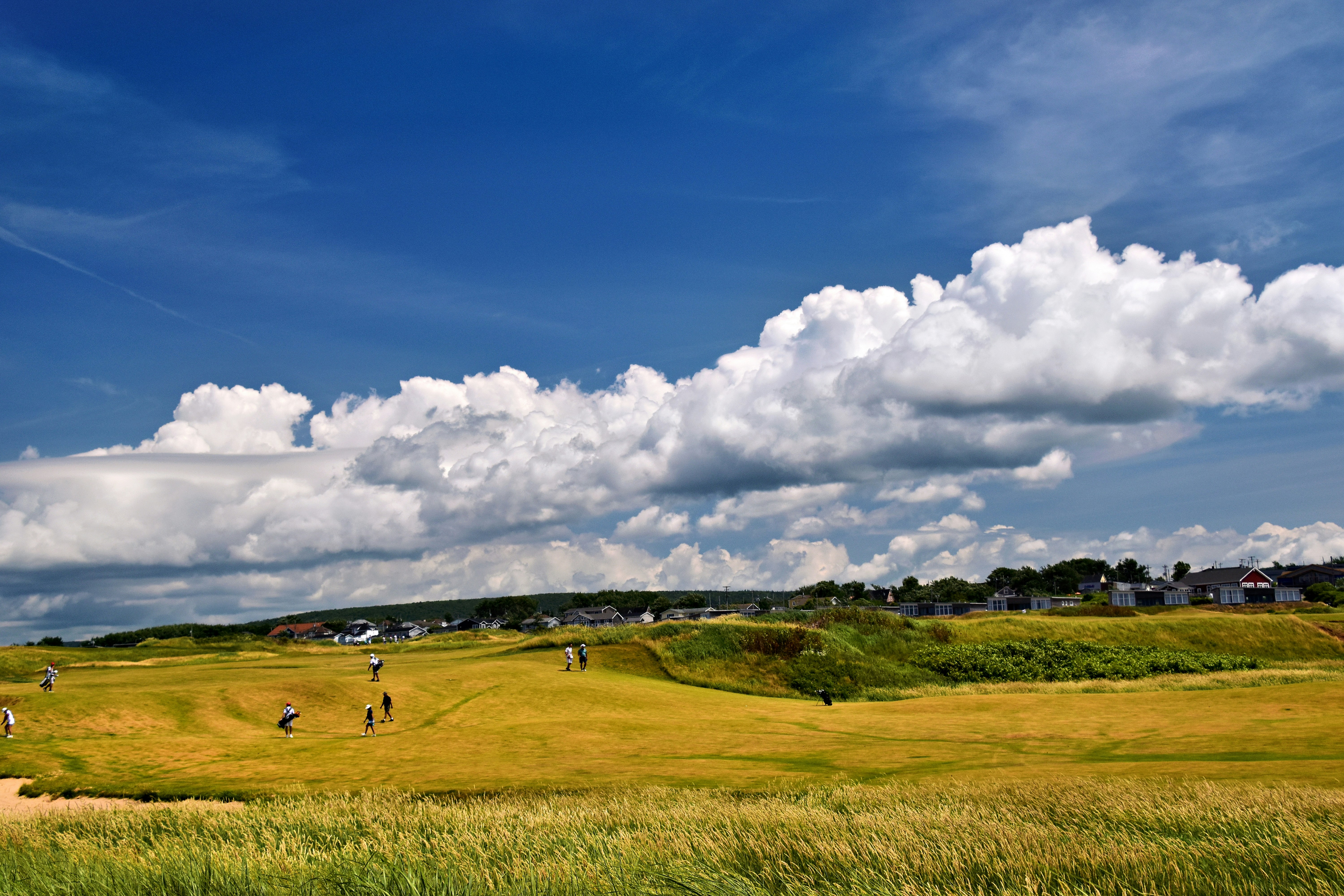 Golfers on a sunny day with green hills and blue sky