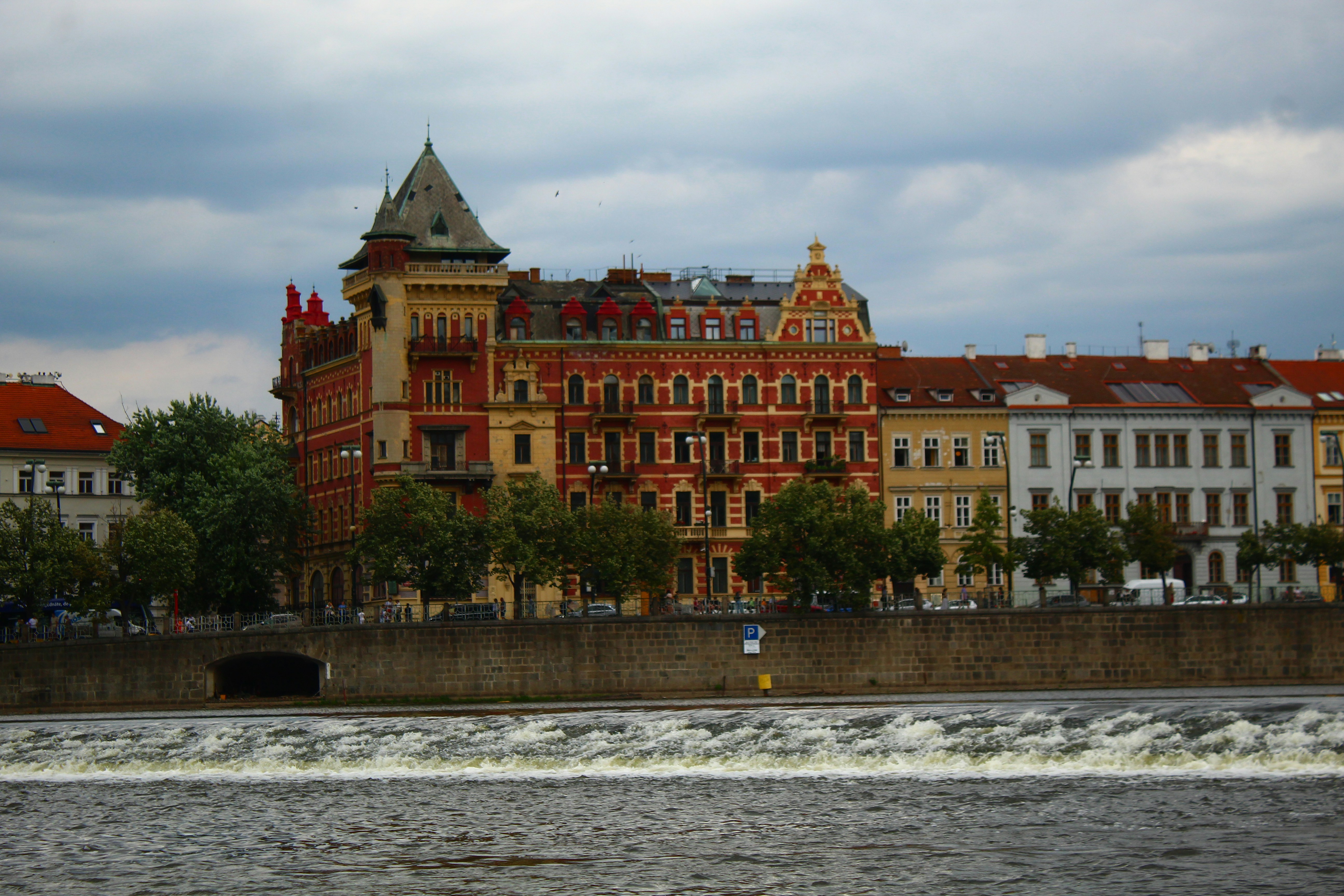 Colorful buildings line a river with a weir.