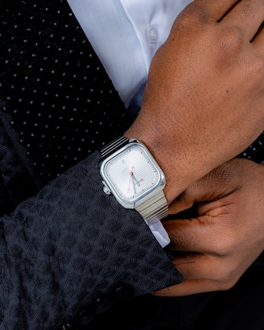 Man's wrist with silver watch and patterned jacket
