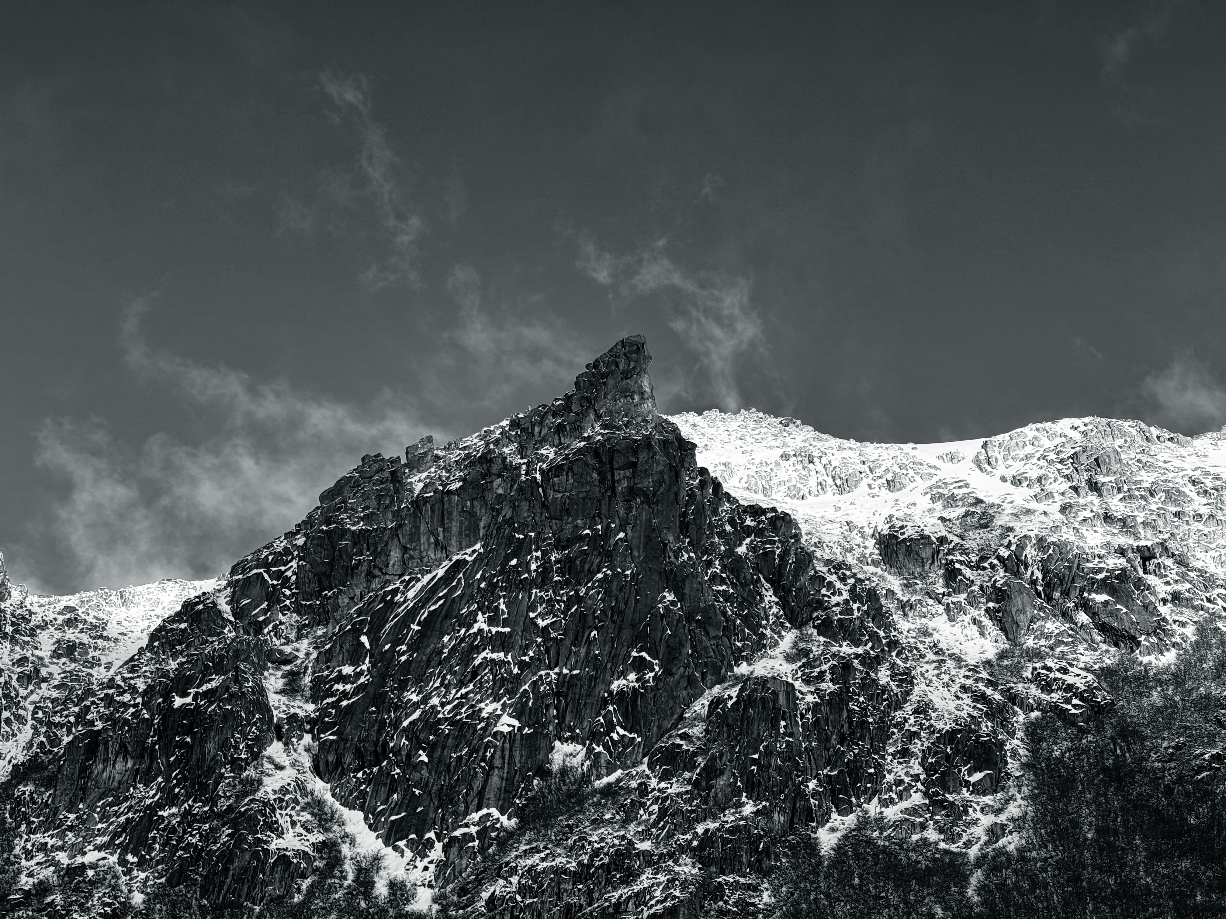 Cerro Catedral em Bariloche, montanha rochosa coberta de neve em preto e branco, com um céu nublado ao fundo. // Cerro Catedral en Bariloche, montaña rocosa cubierta de nieve en blanco y negro, con un cielo nublado de fondo. // Catedral Mountain in Bariloche, snowy rocky mountain in black and white, with a cloudy sky in the background.