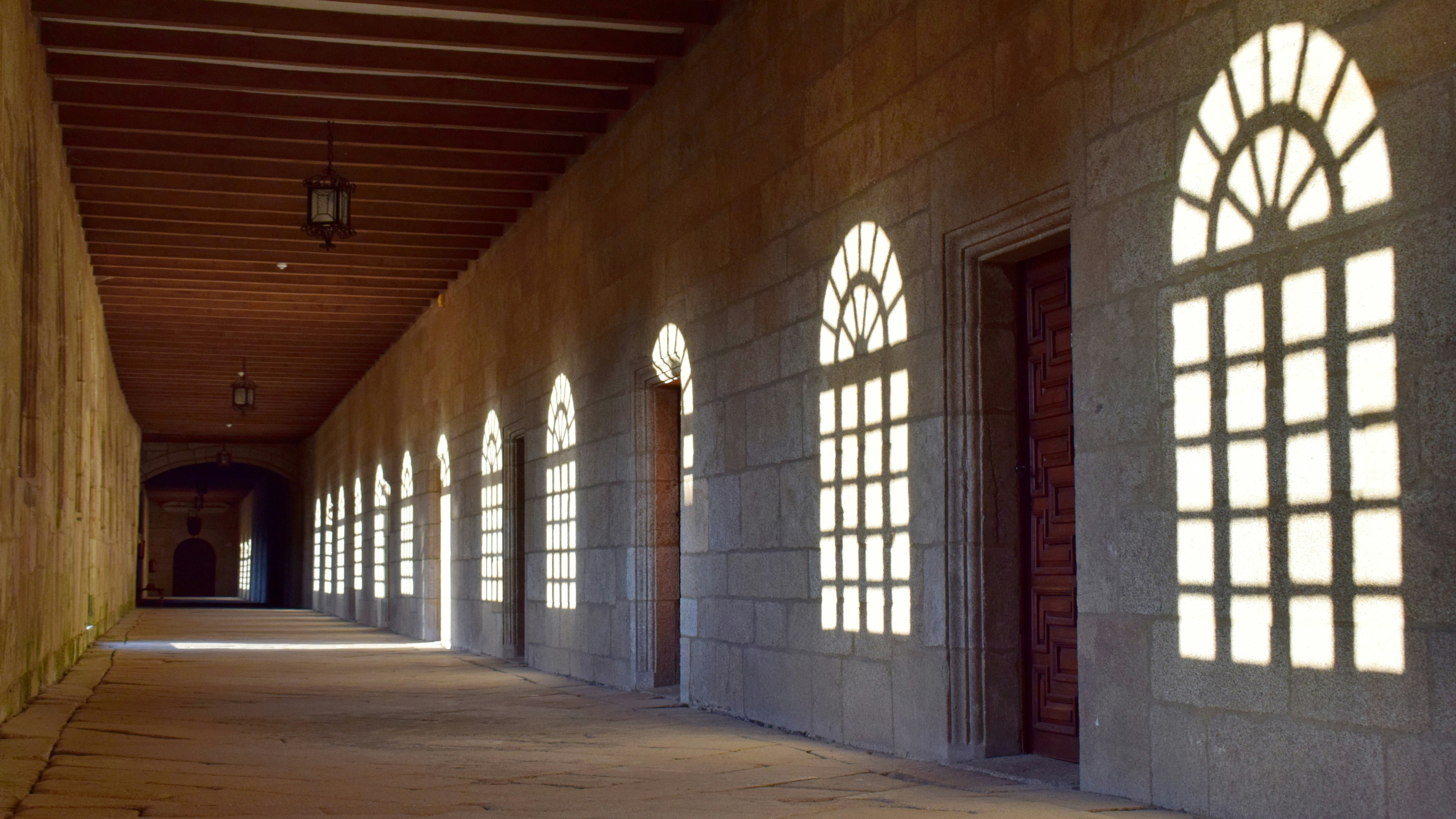 Sunlight streams through arched windows in a long hallway.