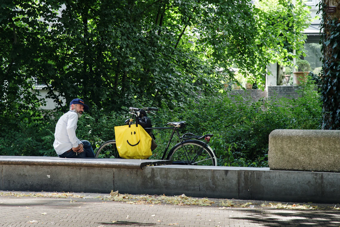 Cyclist resting beside a bicycle with a practical carrying bag