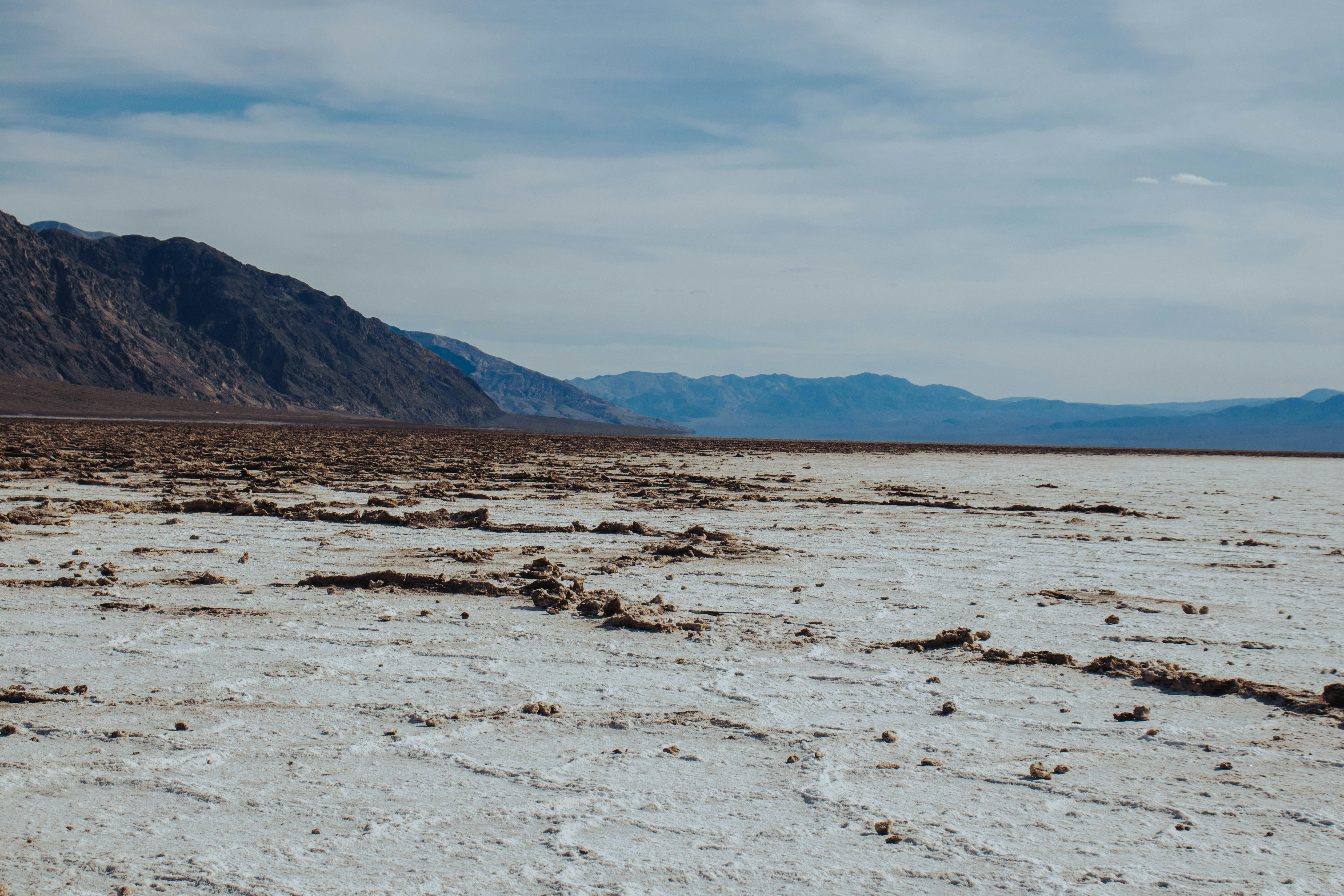 Dry cracked salt flats with distant mountains under sky