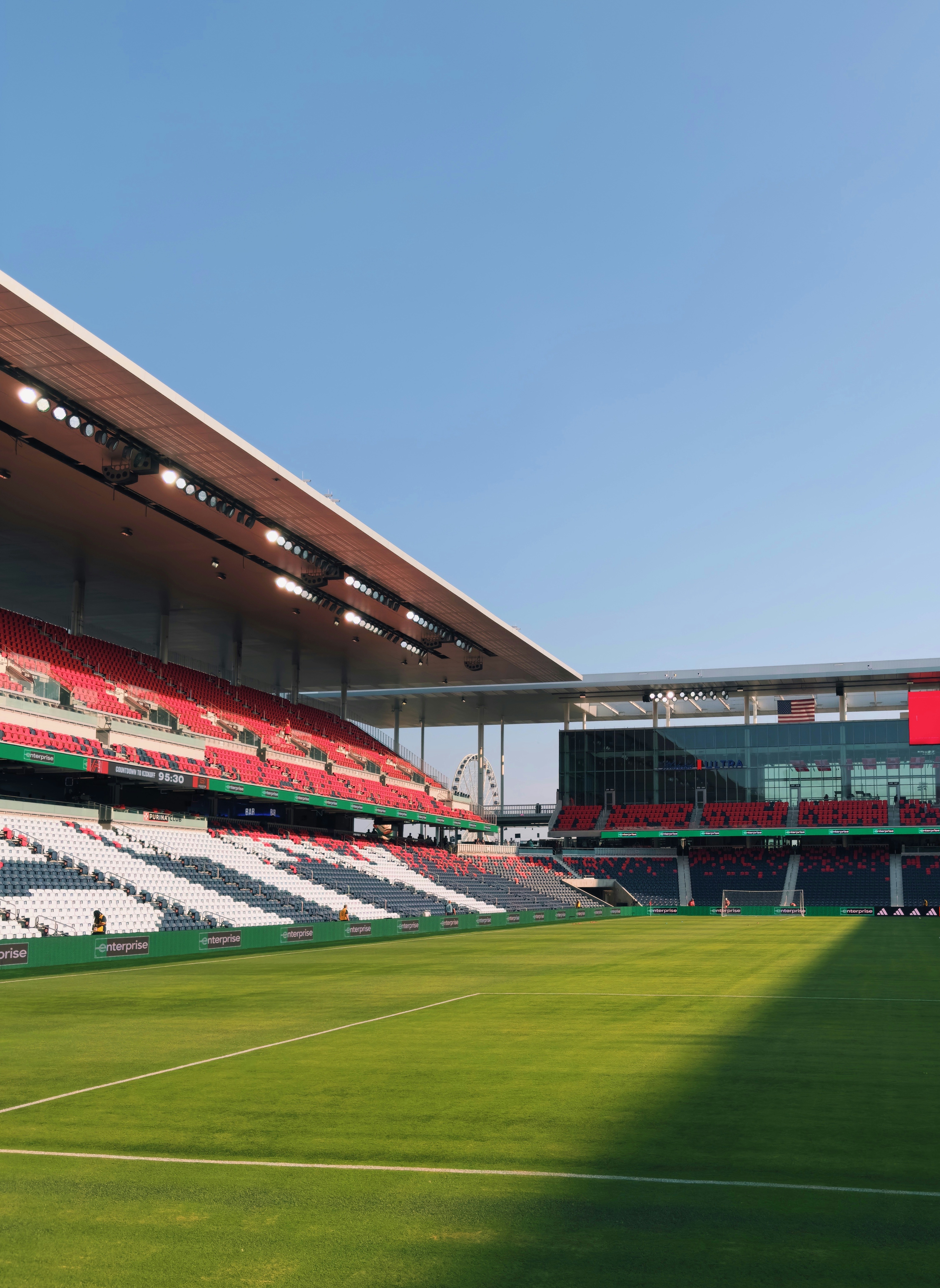 Stadion sepak bola kosong dengan lapangan hijau dan kursi merah