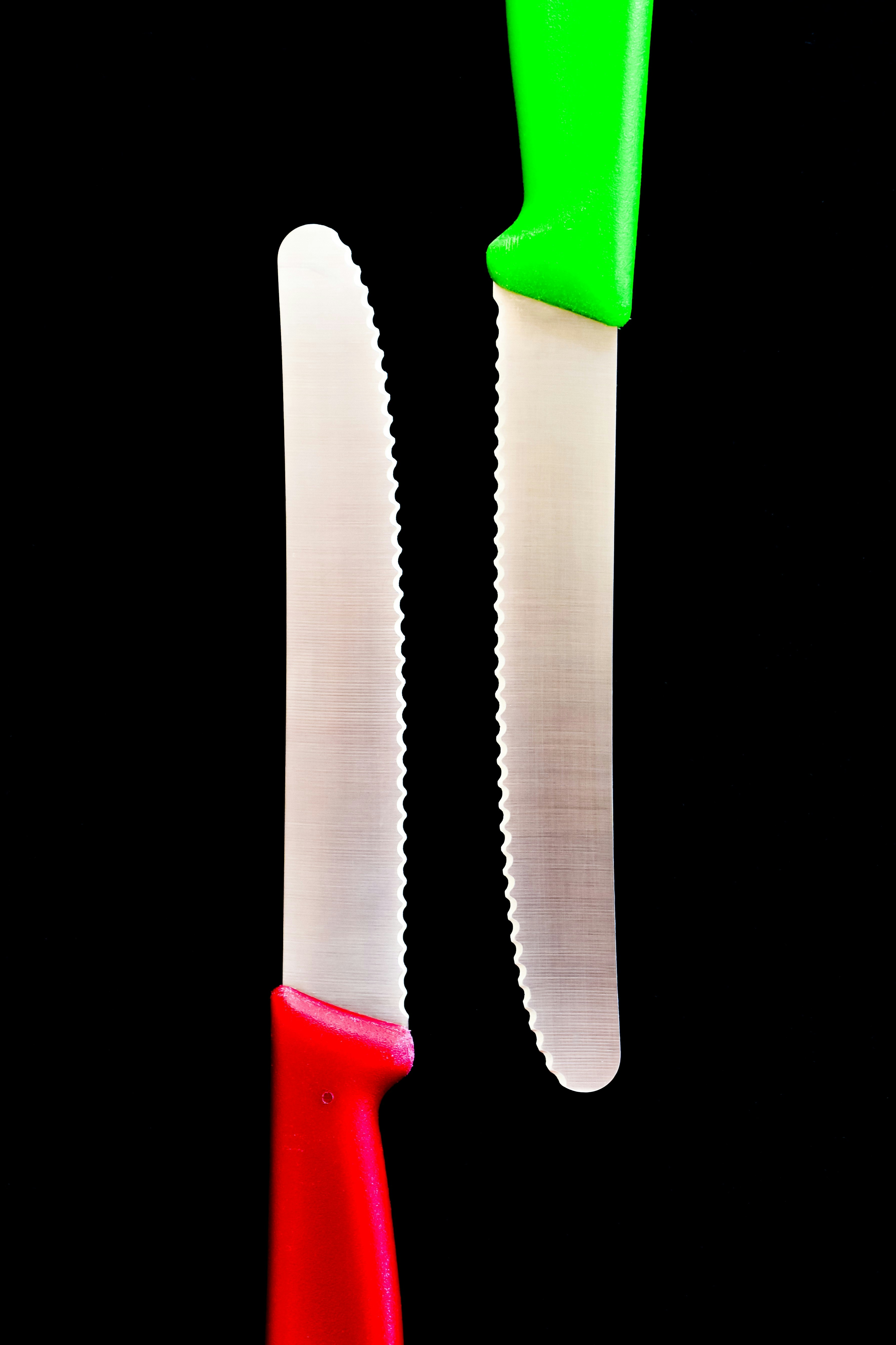 Two serrated knives with red and green handles