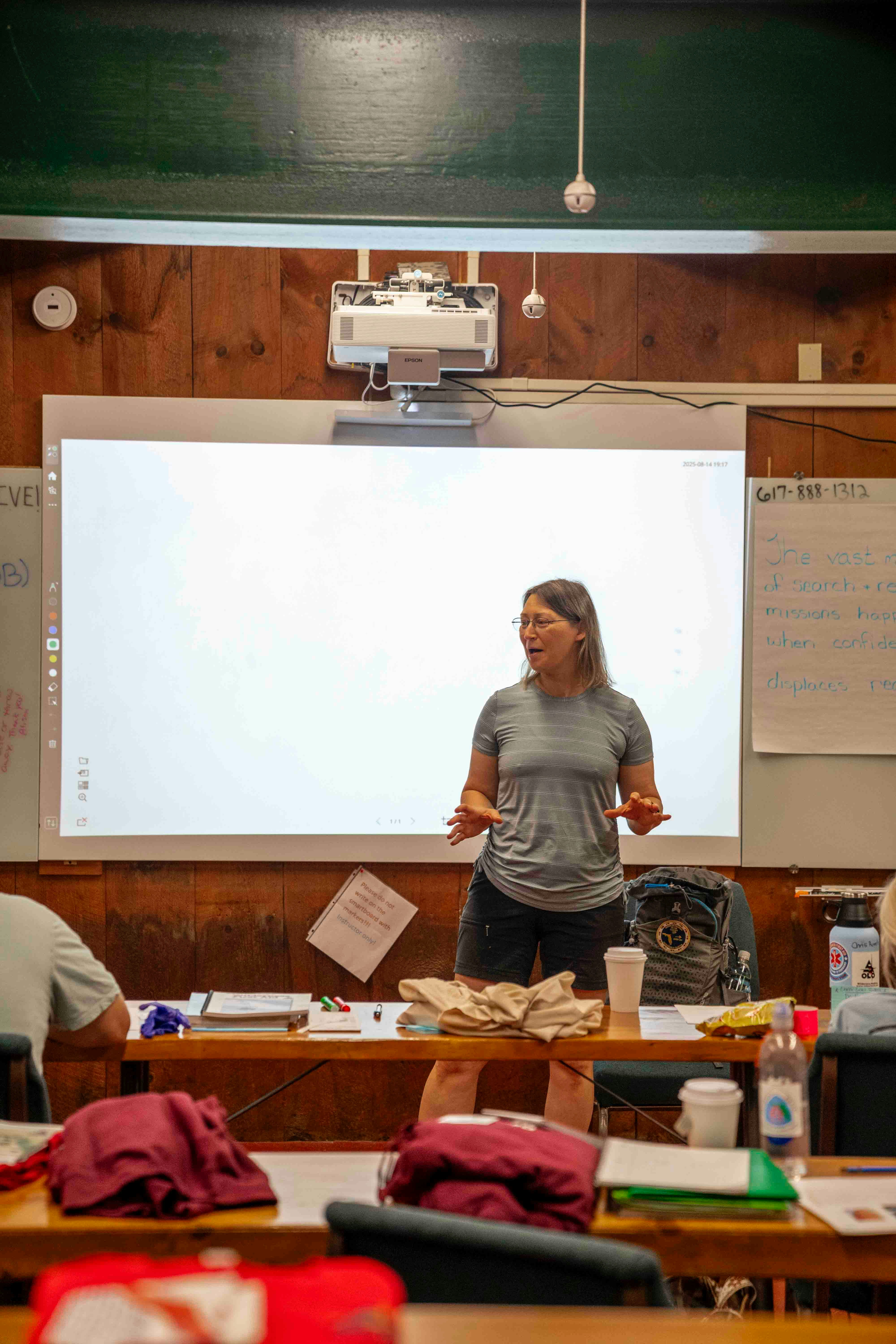 Woman speaking in front of a projector screen in a classroom