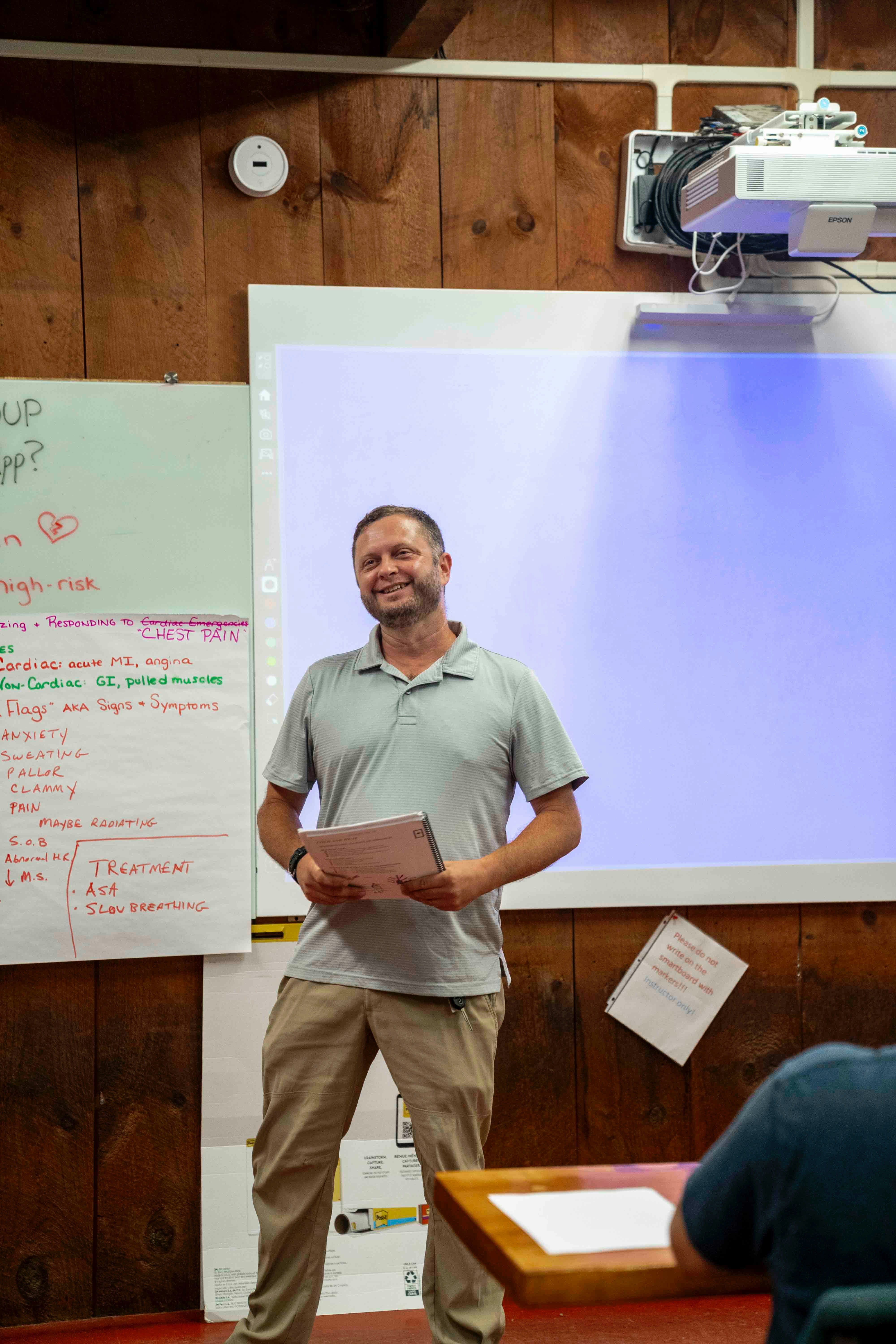 Man standing in front of a whiteboard and projector.