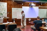 A man presents to an audience in a classroom.