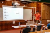 Man presents information on a whiteboard to an audience.