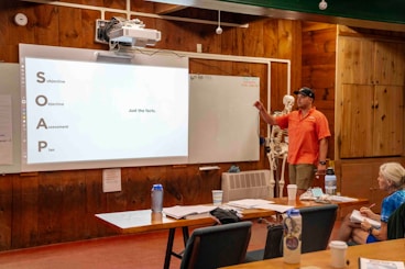 Man presents information on a whiteboard to an audience.