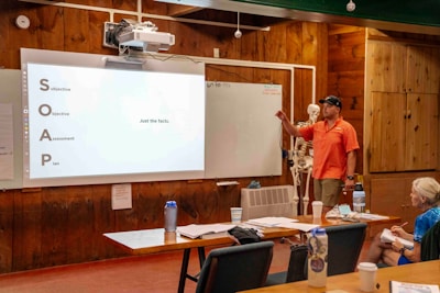 Man presents information on a whiteboard to an audience.