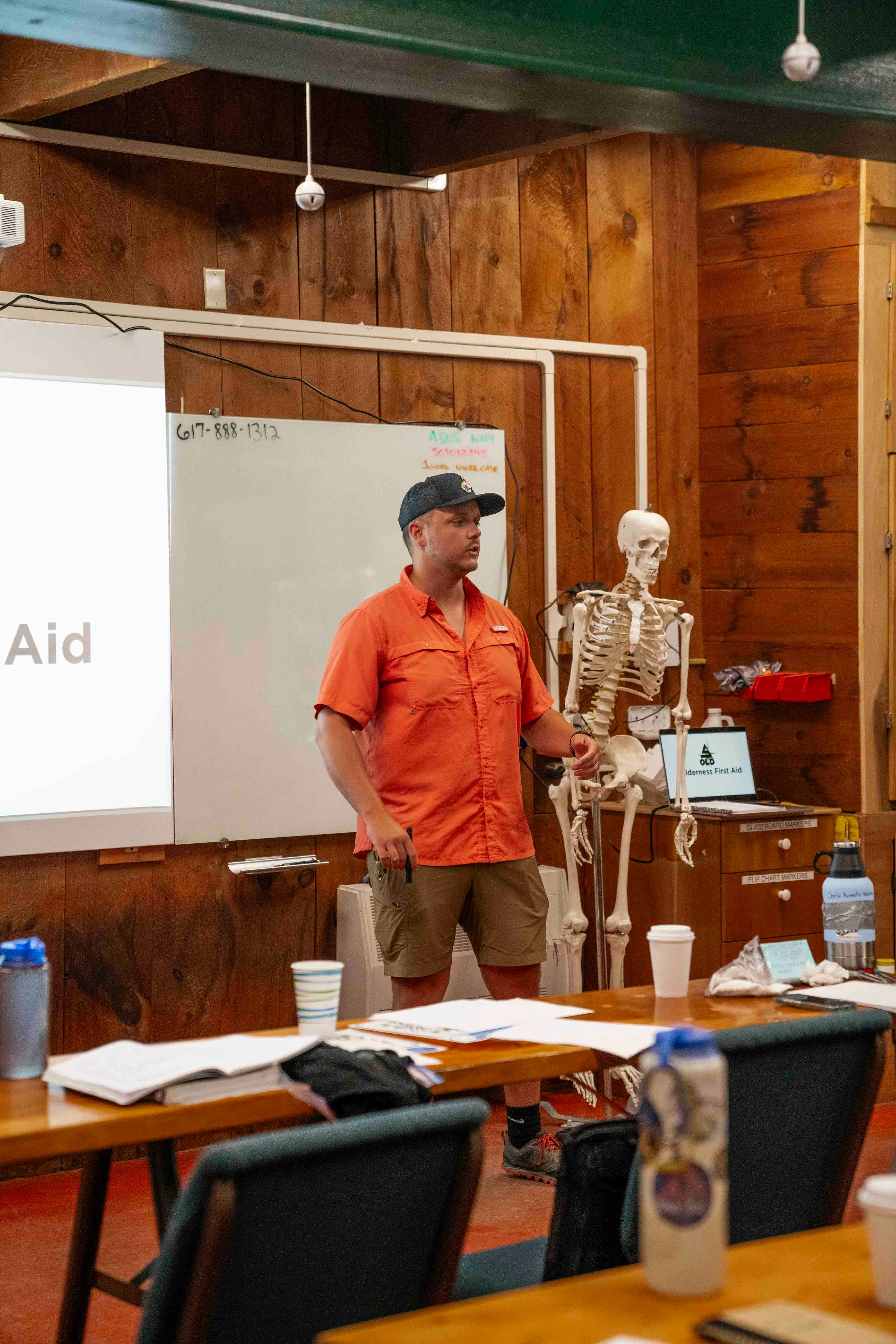 Man teaching with skeleton model in classroom.