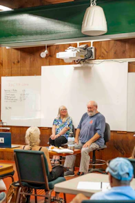 Two people speak to an audience in a classroom