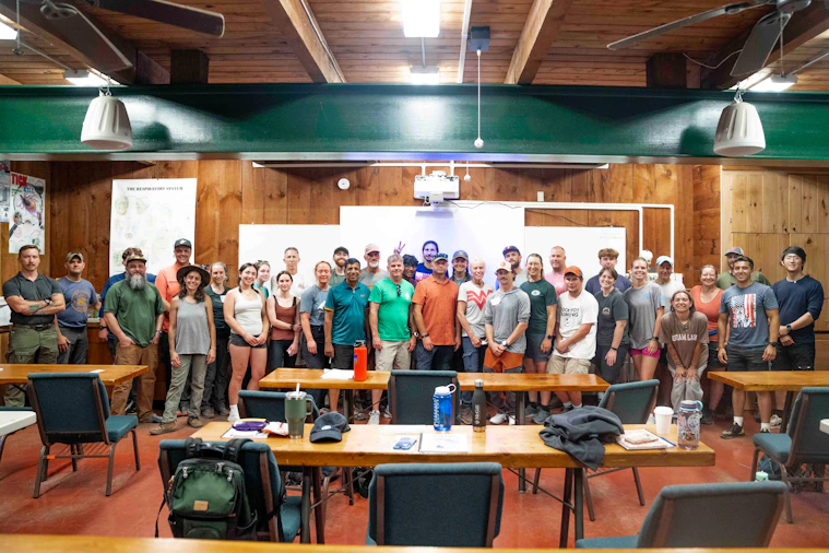 A large group of people stand together indoors.