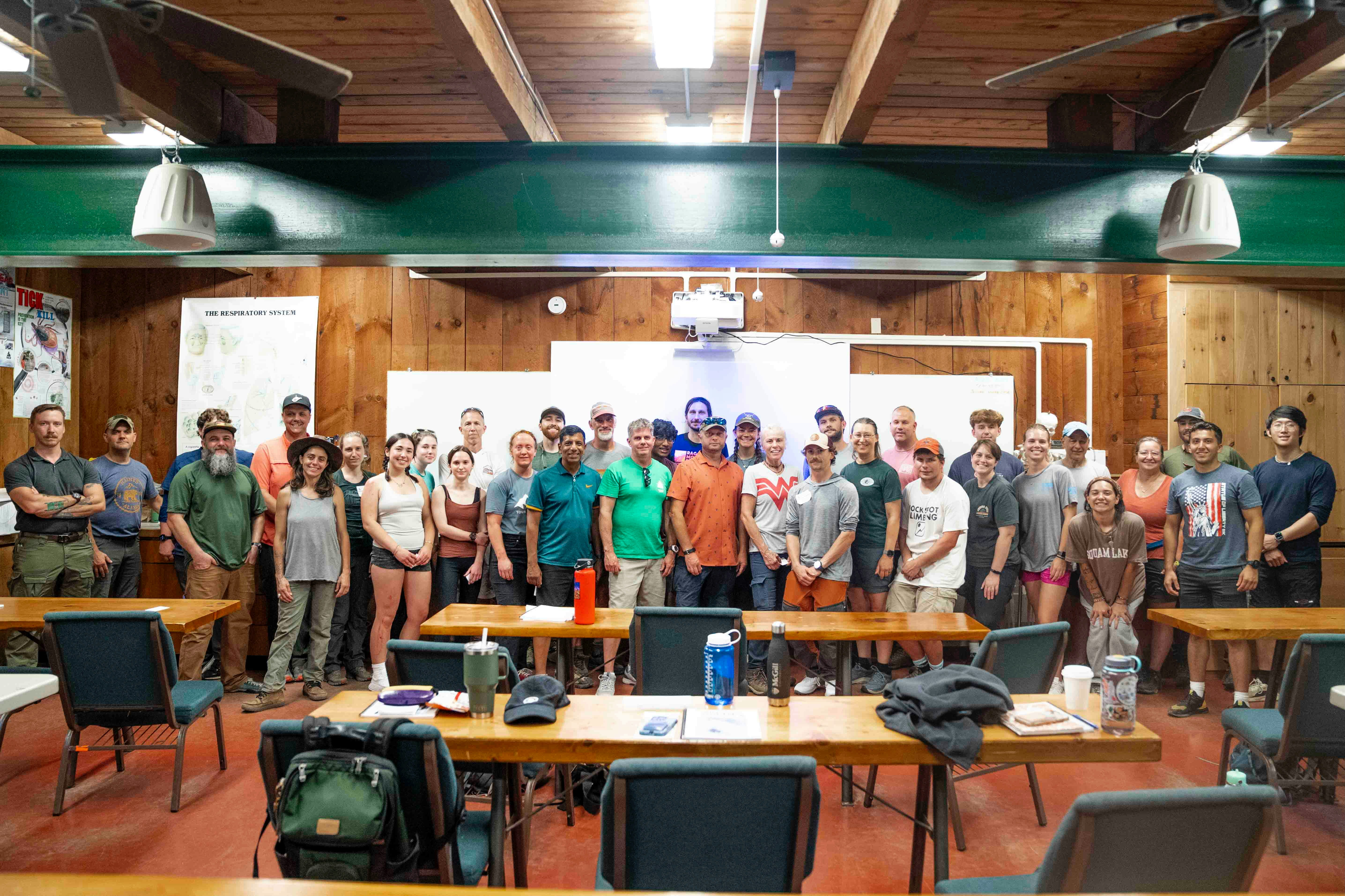 Group of people standing in a room with tables.