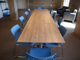 Long wooden table with blue chairs in a room