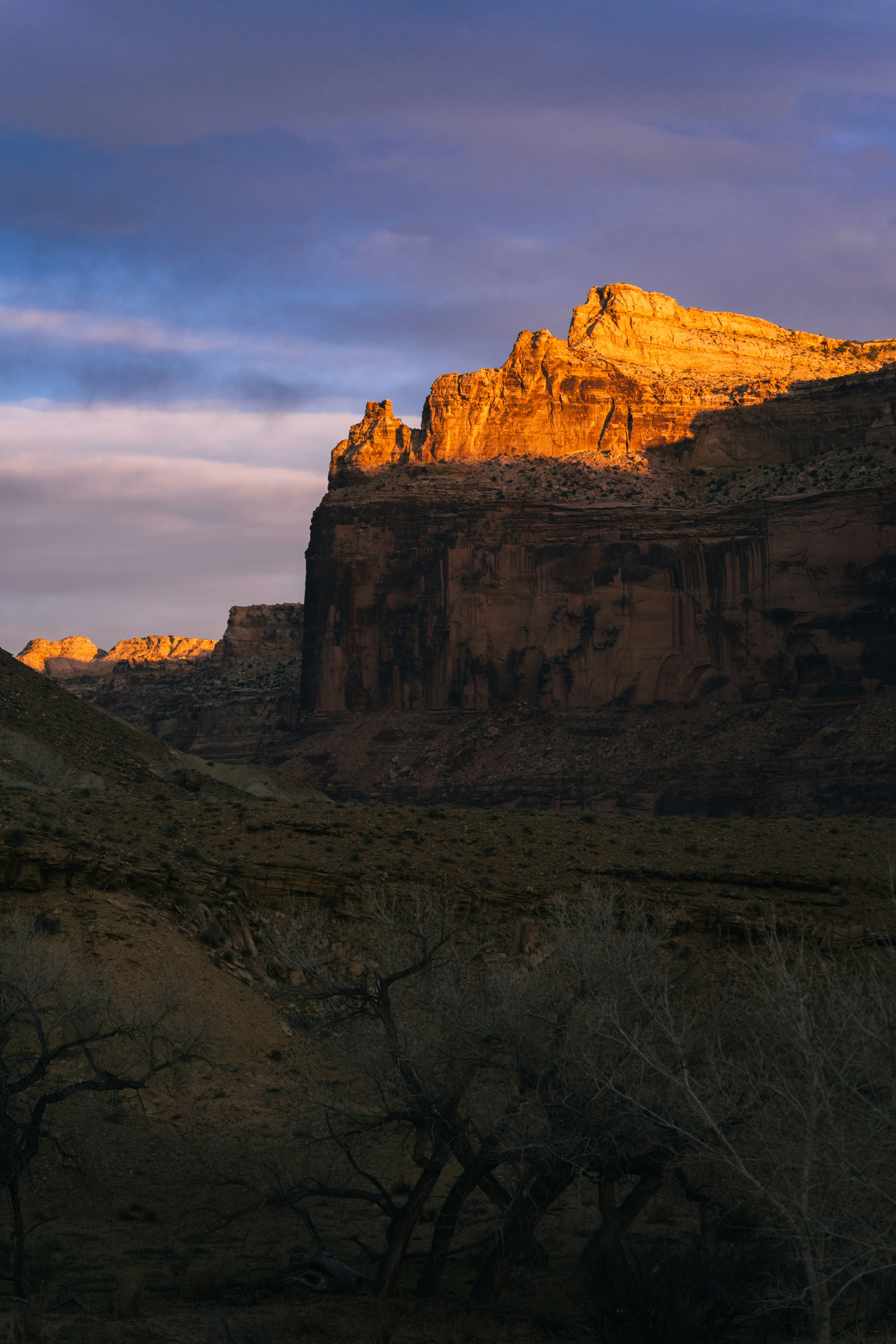 Golden sunlight illuminates a rugged cliff face at sunset.